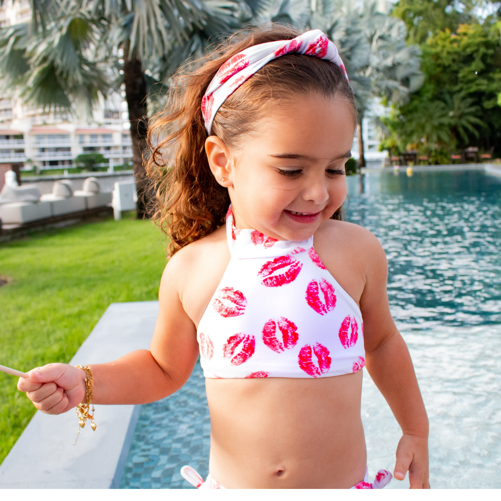 A vibrant Red Kisses bikini for kids, featuring a playful print and made from soft lycra material, perfect for swimming and beach activities.