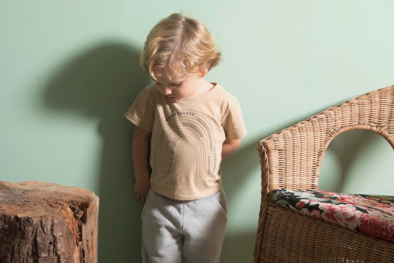 A long sleeve baby shirt in latte color featuring a chocolate rainbow print, made from 100% organic cotton.