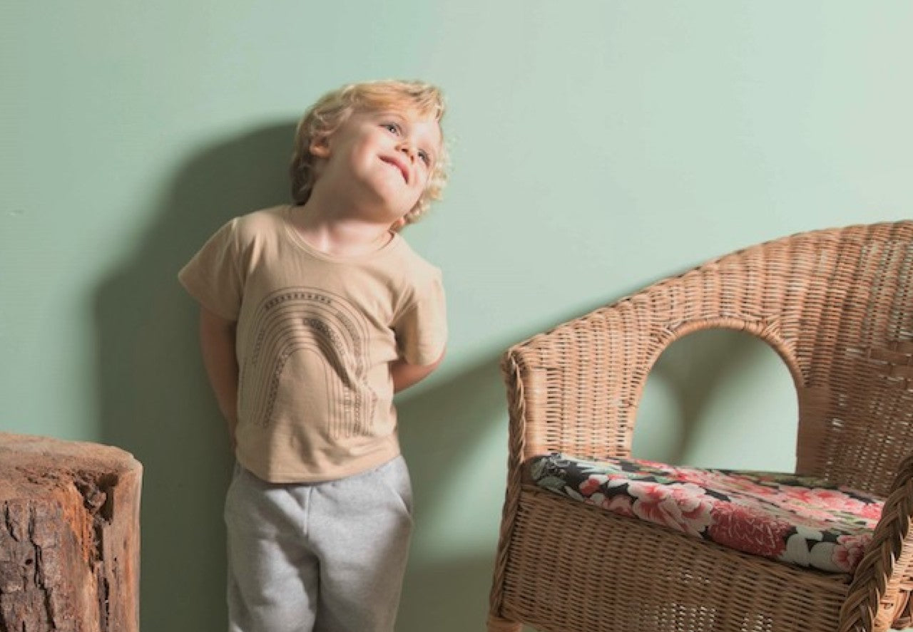 A long sleeve baby shirt in latte color featuring a chocolate rainbow print, made from 100% organic cotton.