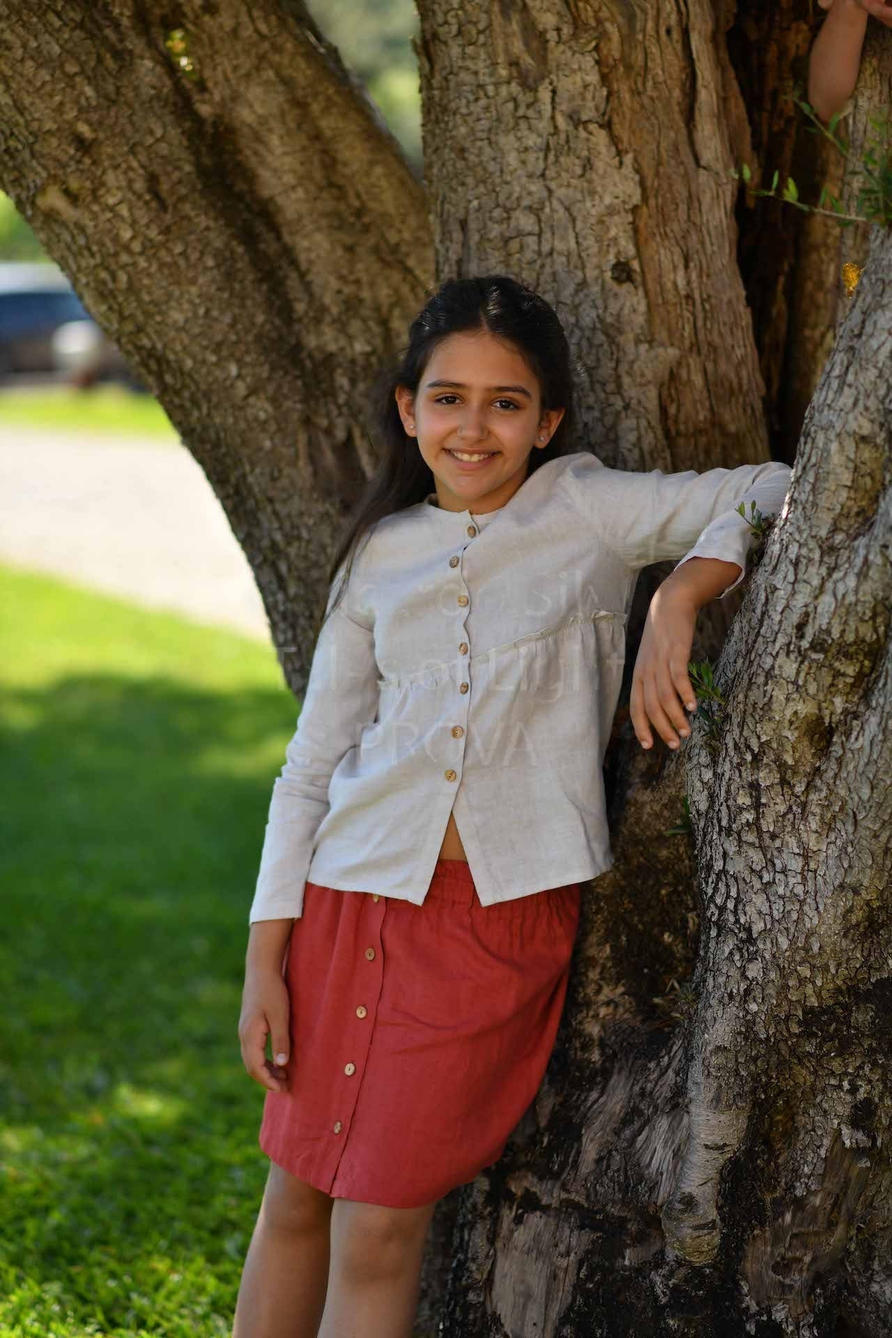 A stylish long-sleeve shirt in creme color with frilled elasticised waist and olive wood button front closure, made from 100% breathable linen.