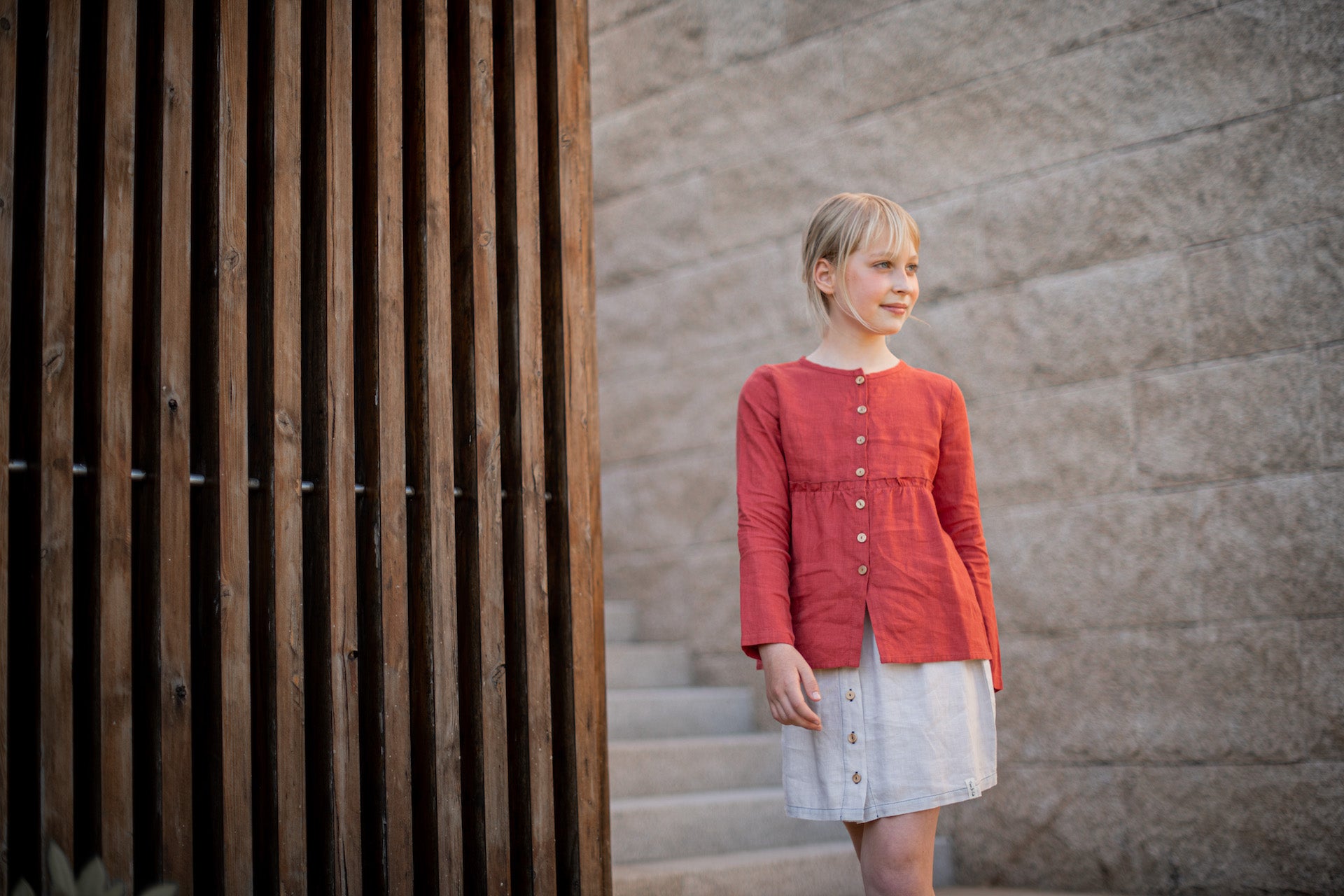 A casual long-sleeve shirt in terracotta color with olive wood buttons and a frilled elasticised waist, made from 100% breathable linen.