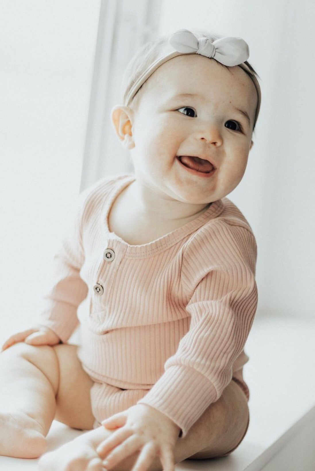 A soft ribbed bodysuit for babies, made from cotton and spandex, showcasing its stylish design and available sizes.