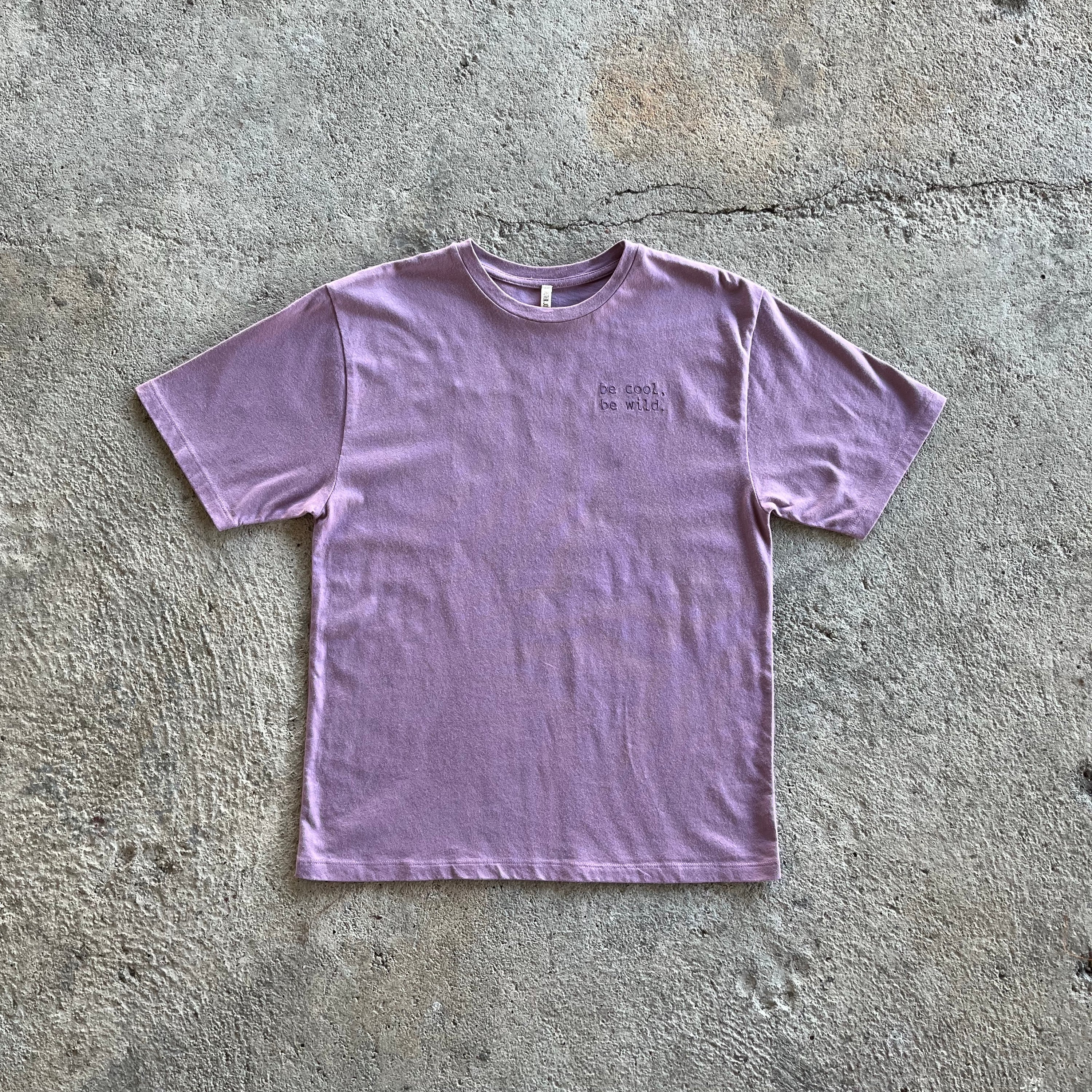 Beet Orchid T-Shirt featuring a loose, boxy style with short sleeves and embroidered text 'Be cool, Be Wild' on the side.