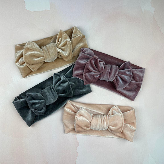 A soft velvet knot headband in a rich color, featuring a stylish bow, perfect for babies and toddlers during fall and winter.