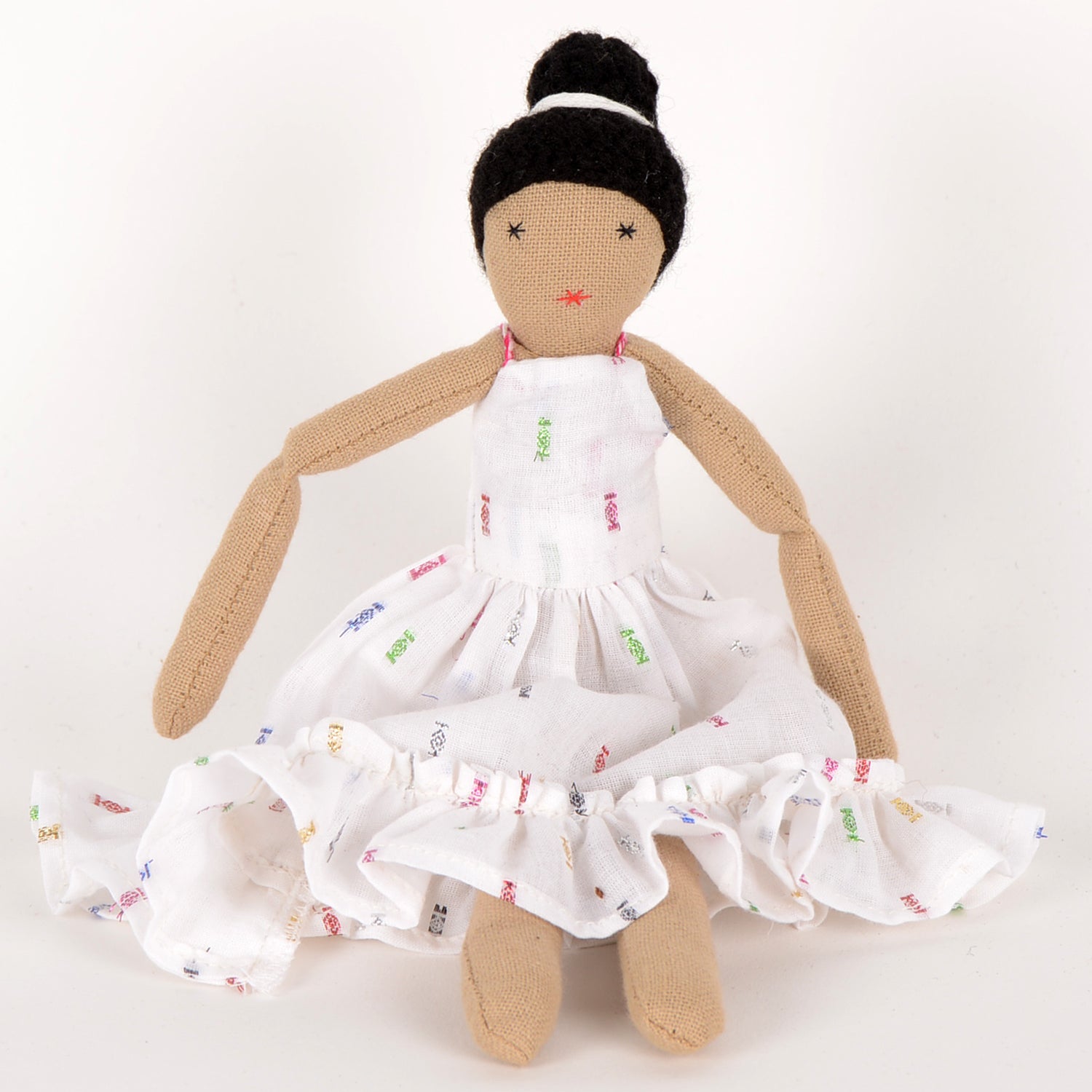 Calla Mini doll dressed in a stylish cotton outfit with geometric motifs, featuring a bun hairstyle and colorful ribbon, showcasing elegance and craftsmanship.