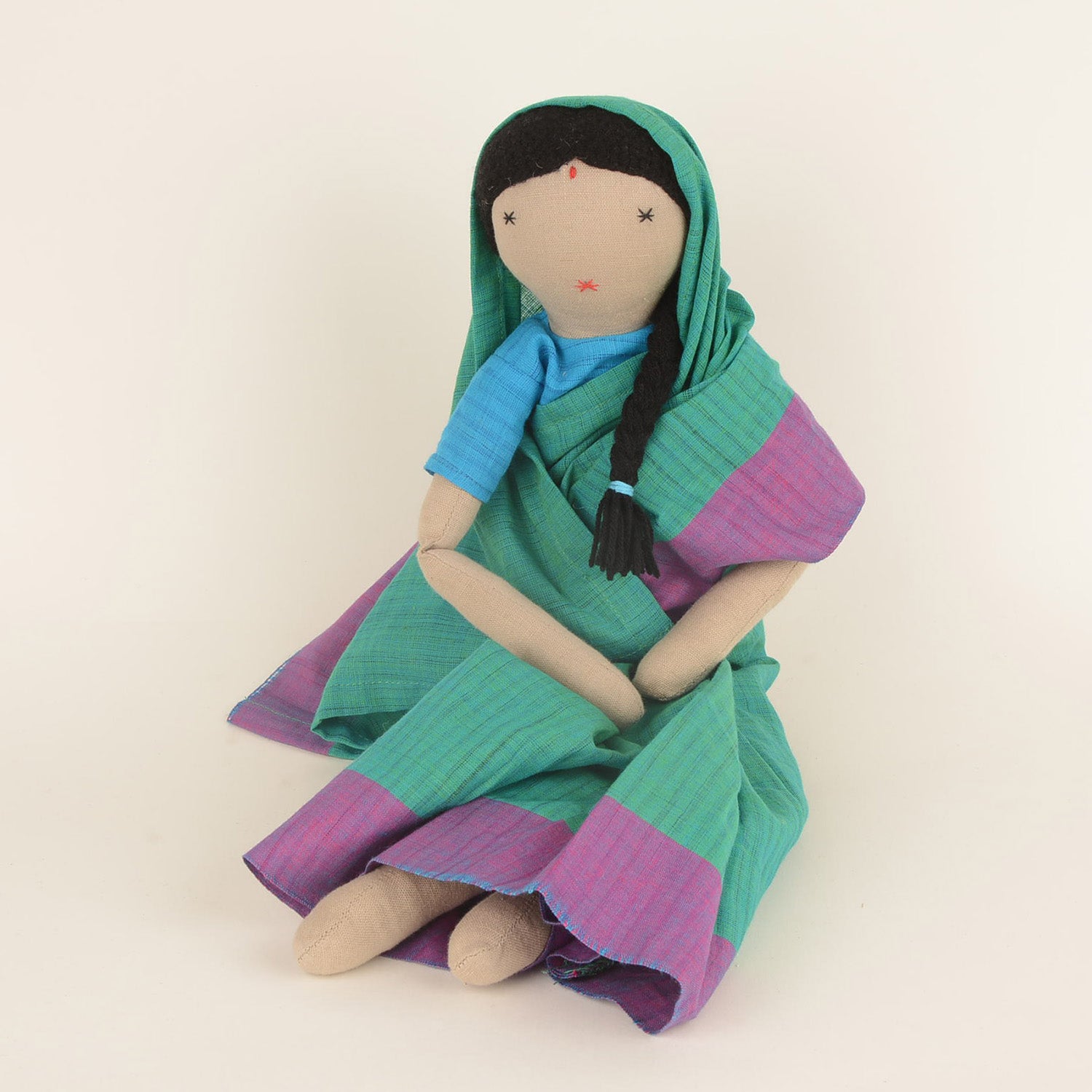 Chachi, the handcrafted doll in a colorful Indian sari, symbolizing joy and empowerment, with a bindi on her forehead and soft woollen hair.