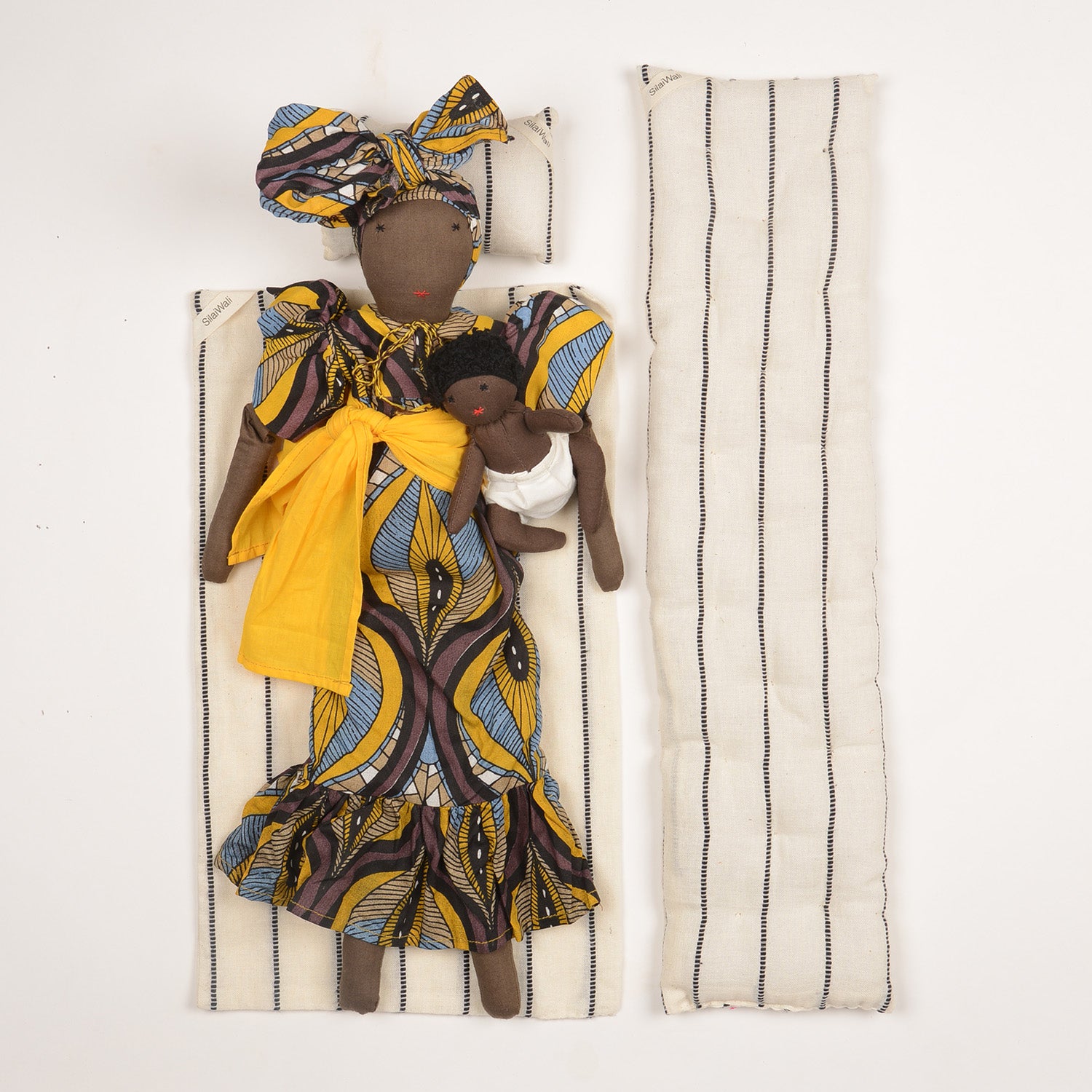 Imani doll with vibrant African print kaftan and regal turban, holding a baby, symbolizing maternal strength and cultural diversity.