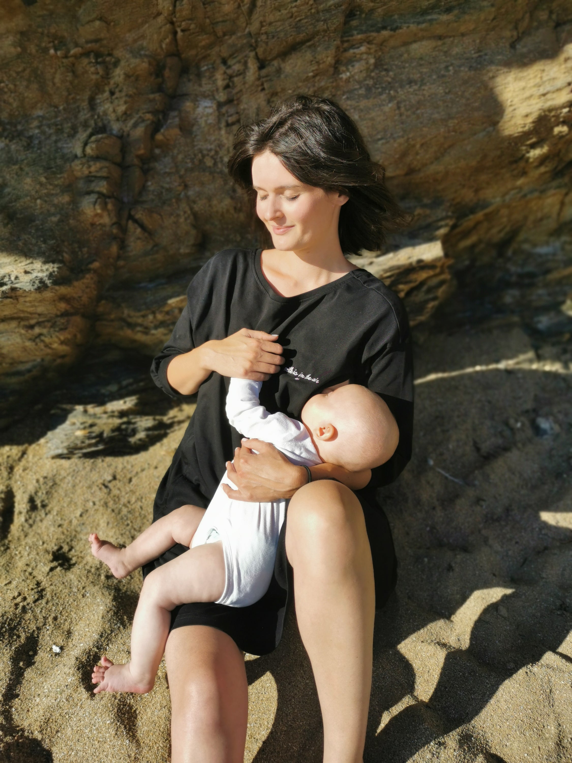 A stylish black breastfeeding dress with pink embroidery, featuring ruffles and YKK zippers for easy nursing access.