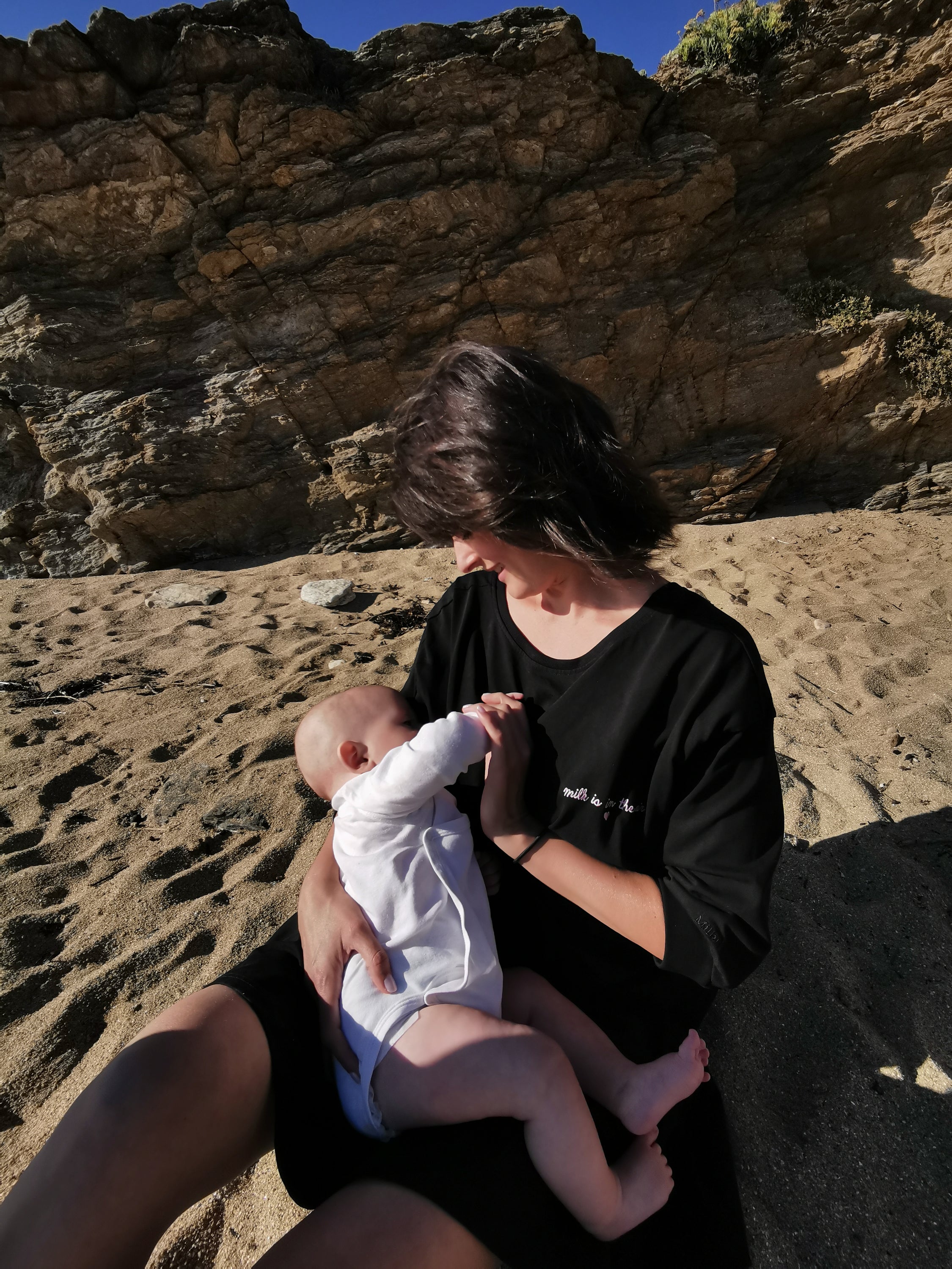 A stylish black breastfeeding dress with pink embroidery, featuring ruffles and YKK zippers for easy nursing access.