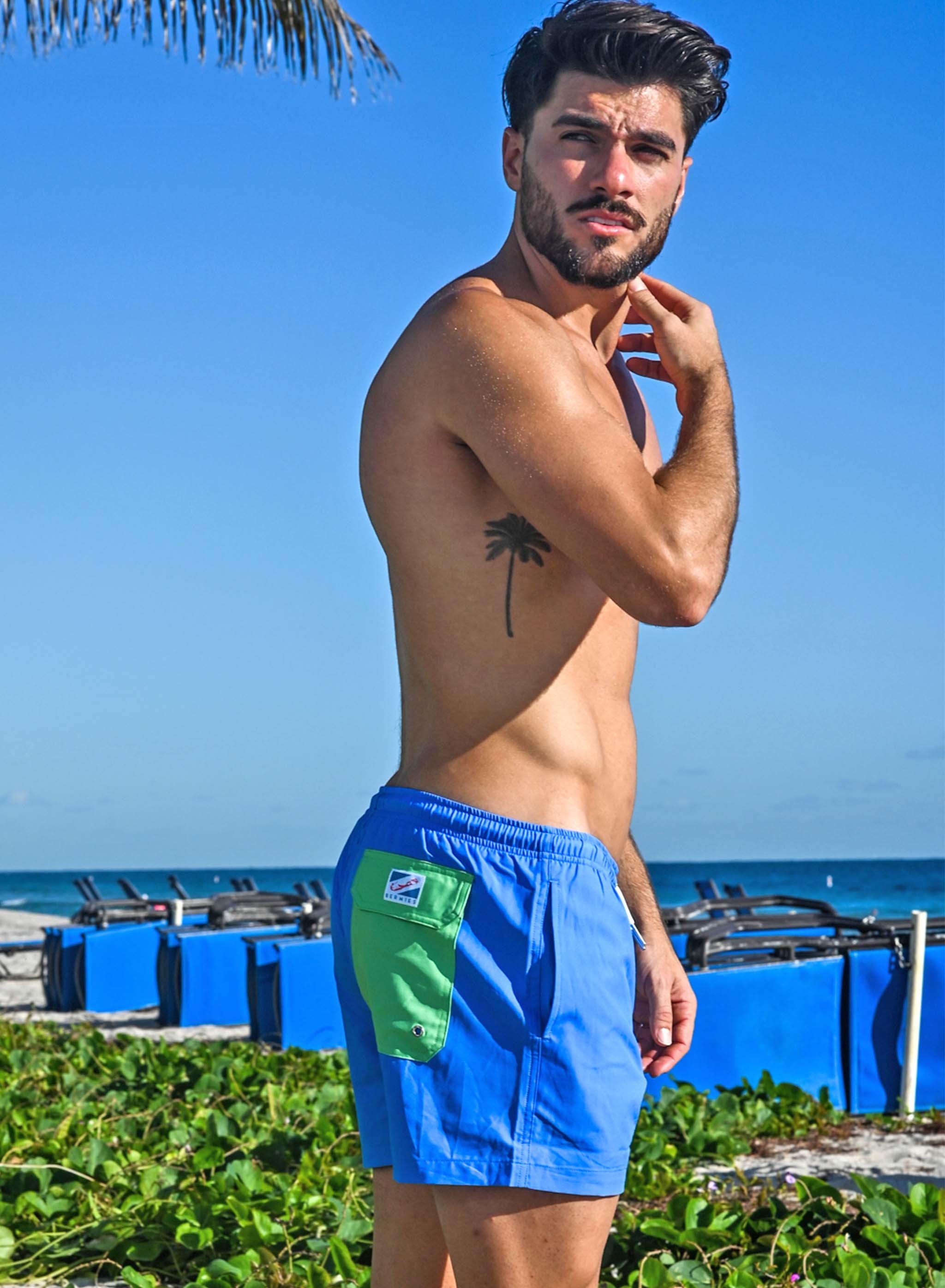 Blue swim trunks with green pocket, featuring a stylish design and eco-friendly materials.