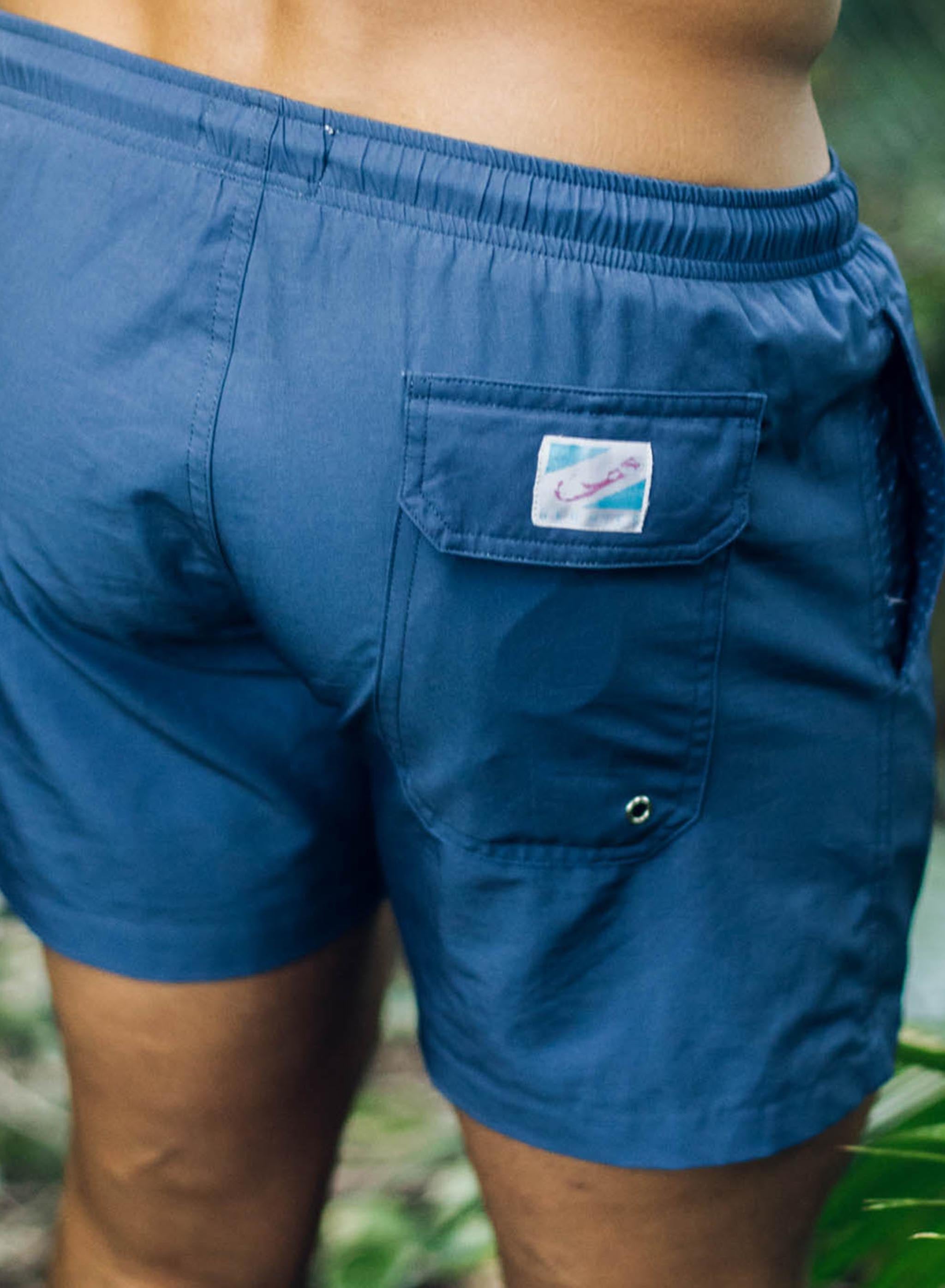 Navy swim trunks made from recycled materials, featuring a stylish design and comfortable mesh liner.