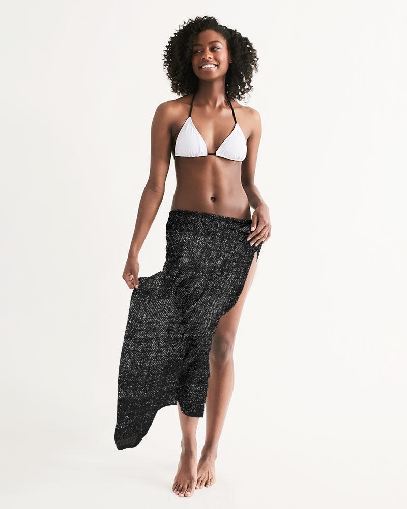 A lightweight sheer sarong swimsuit cover-up wrap in distressed black, elegantly draped over a beach chair, showcasing its flowy fabric and self-tie closure.