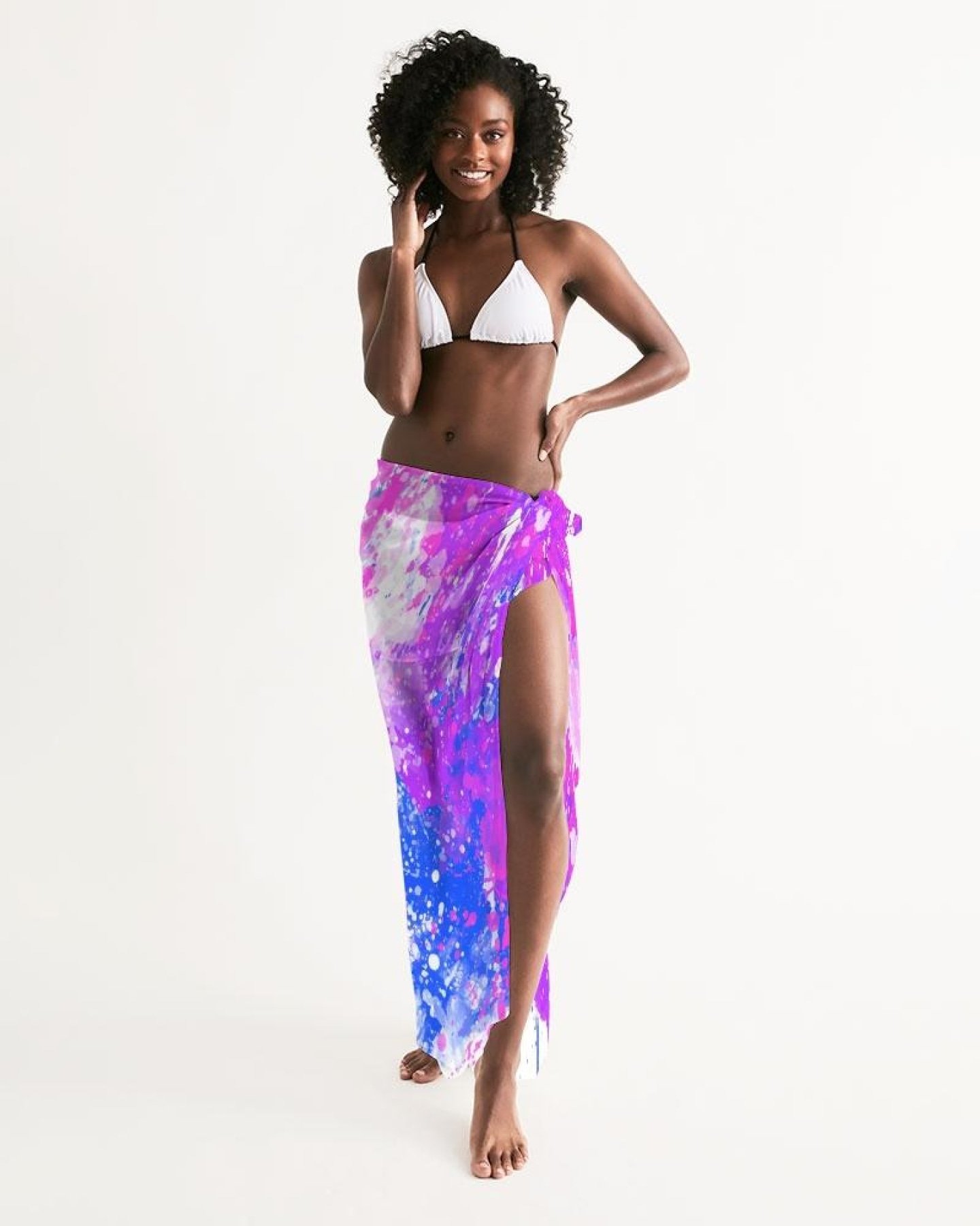 A lightweight sheer sarong swimsuit cover up wrap in purple tie dye, elegantly draped on a beach setting.