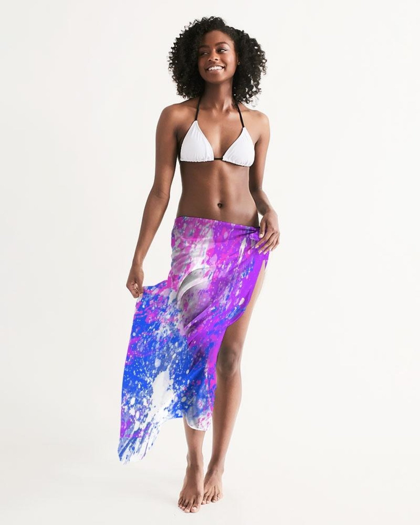 A lightweight sheer sarong swimsuit cover up wrap in purple tie dye, elegantly draped on a beach setting.