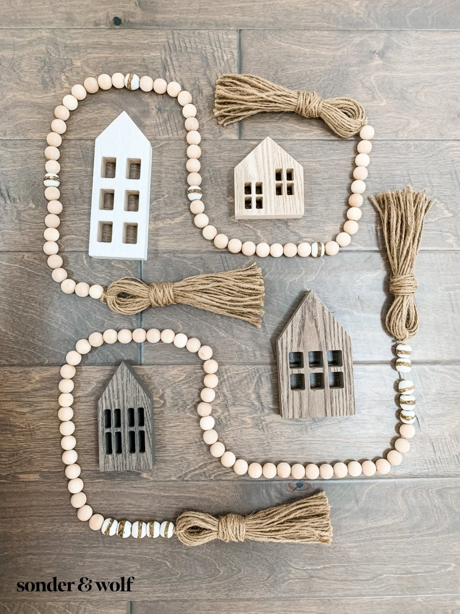 A 4ft handmade wood bead garland featuring light unfinished wood beads and four distinctive White Kente Krobo beads, adorned with jute tassels.