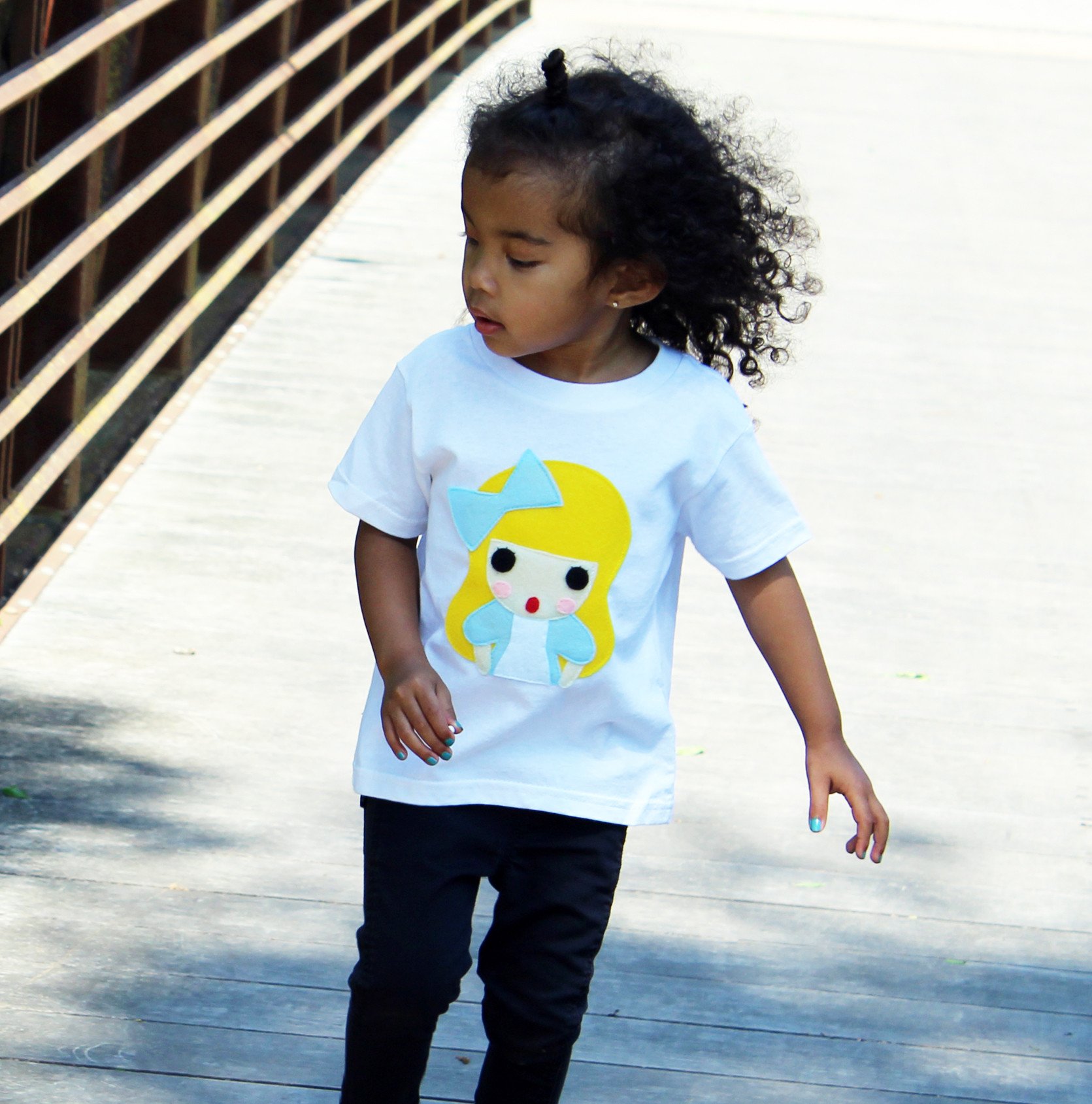 A colorful handmade kids t-shirt featuring an appliqué design of Alice from Alice's Adventures in Wonderland, crafted with eco-friendly materials.