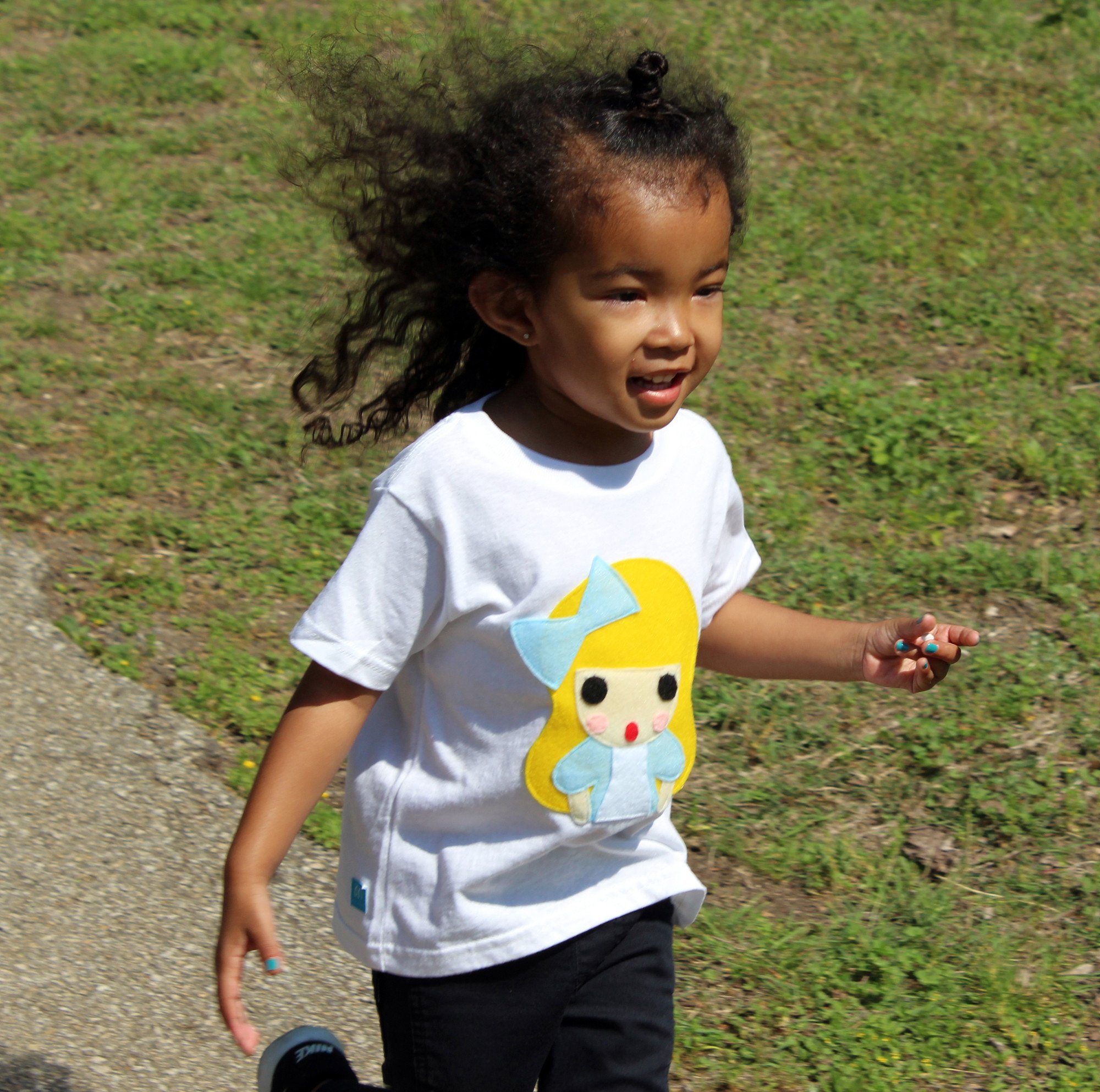 A colorful handmade kids t-shirt featuring an appliqué design of Alice from Alice's Adventures in Wonderland, crafted with eco-friendly materials.