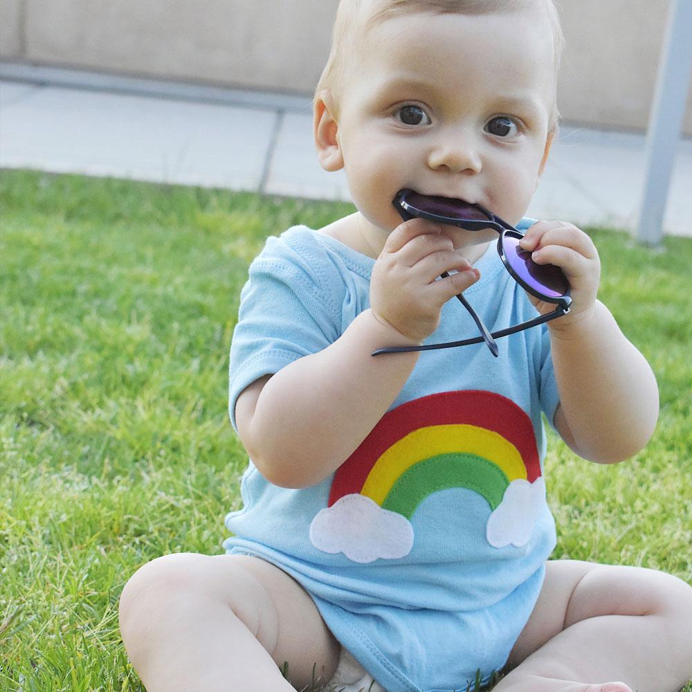 Aloha Rainbow Infant Bodysuit featuring a vibrant rainbow design on a soft blue background, handmade with appliquéd felt pieces.