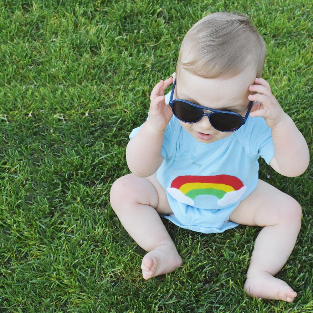 Aloha Rainbow Infant Bodysuit featuring a vibrant rainbow design on a soft blue background, handmade with appliquéd felt pieces.