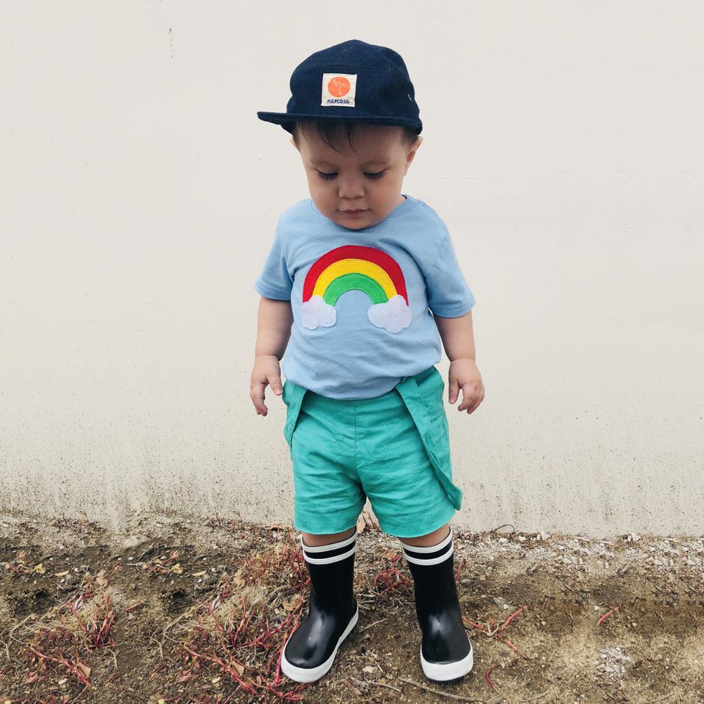 Aloha Rainbow Kids Baby Blue Shirt featuring a colorful rainbow design on a soft blue background, perfect for boys and girls.