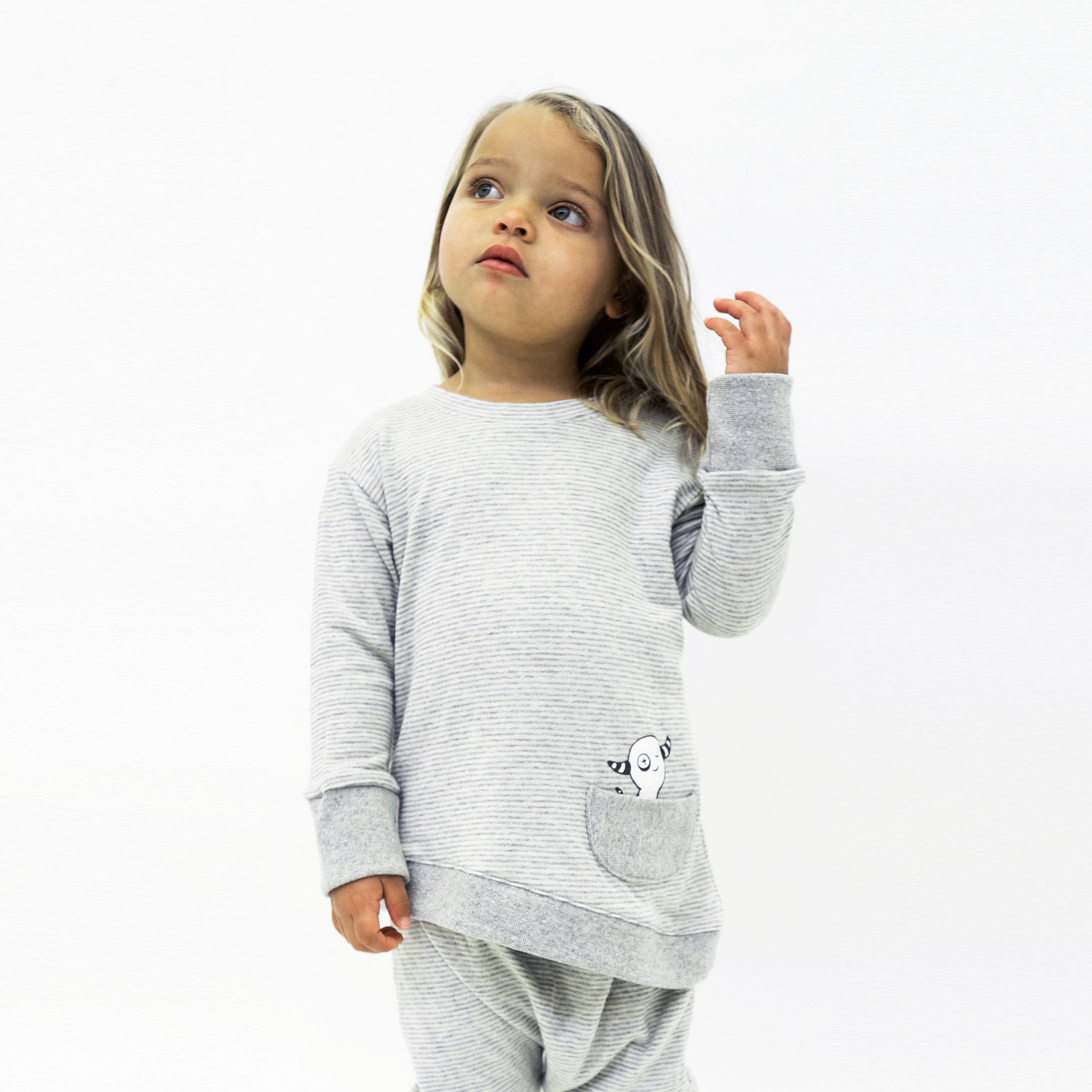 Asymmetric Pullover in Grey Skinny Stripes featuring a monster peek-a-boo front pocket and thumbholes for toddlers.