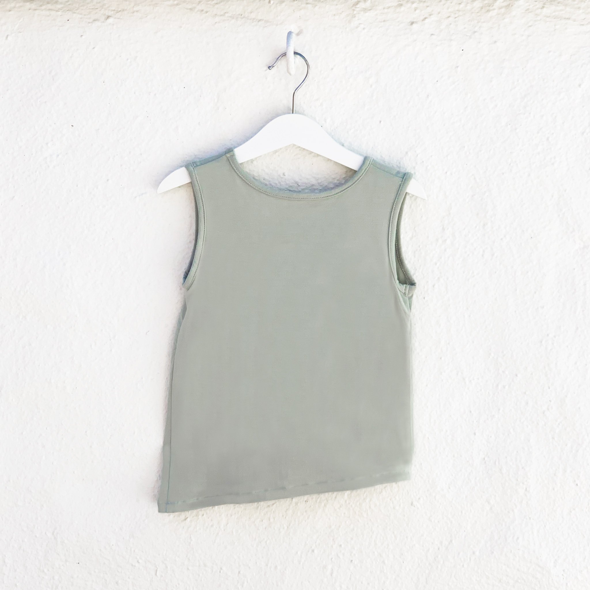 Asymmetric Tank in Desert Sage featuring a unique hem and monster pocket, made from soft rayon modal fabric.