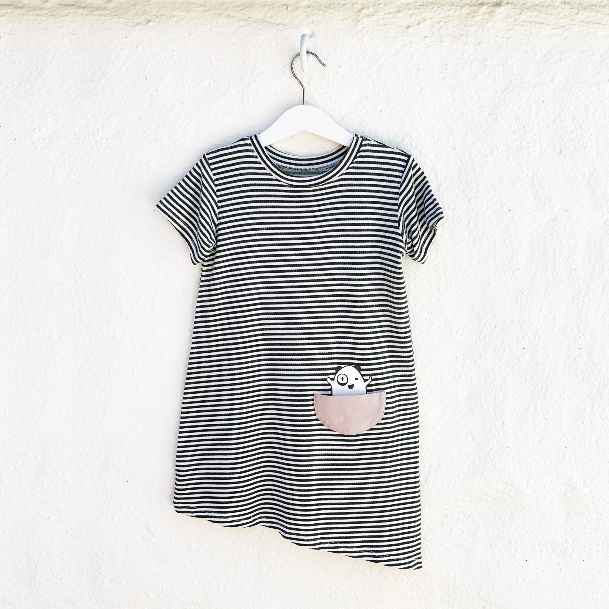 Asymmetric T-shirt Dress in black and white stripes with a monster peek-a-boo pocket, perfect for toddlers.