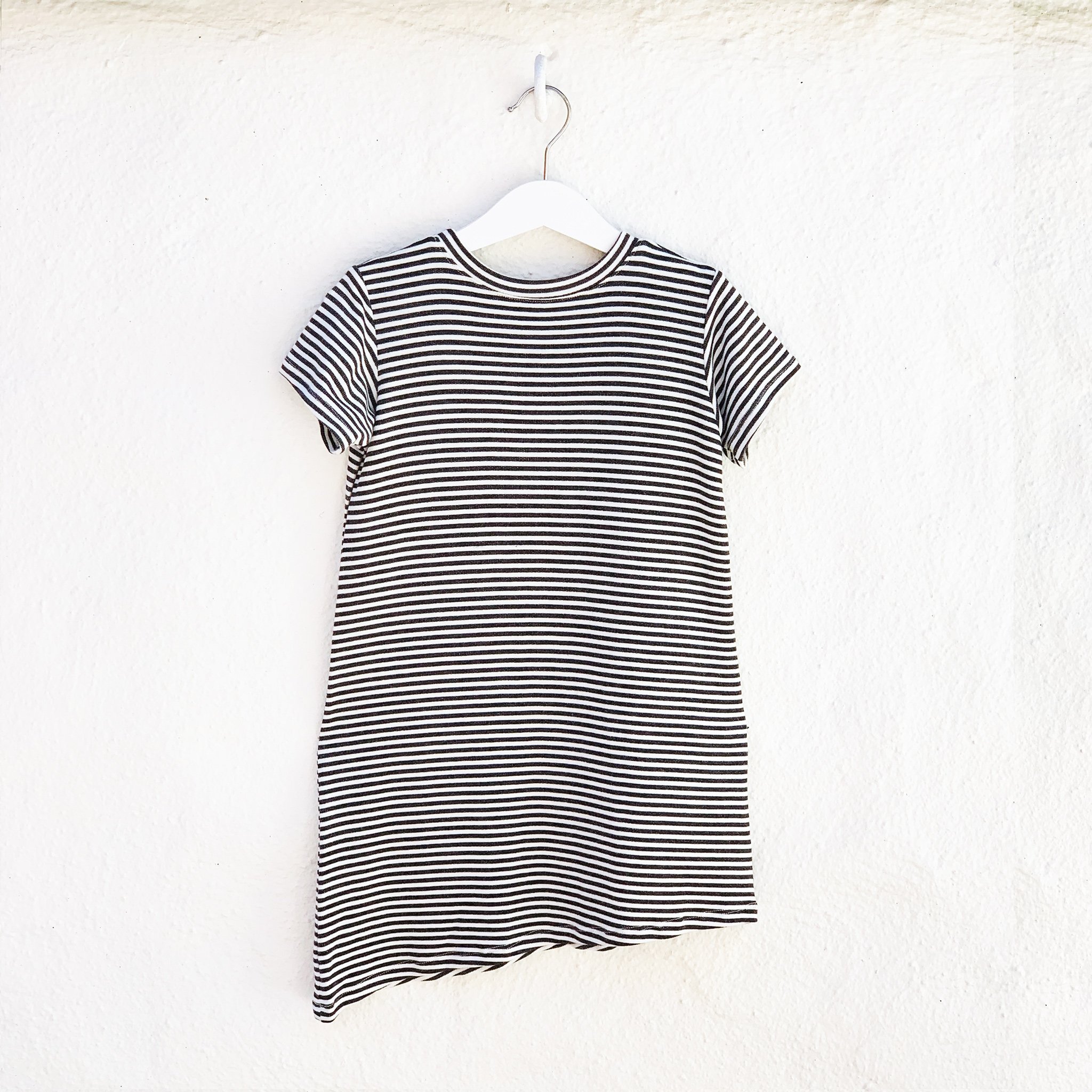 Asymmetric T-shirt Dress in black and white stripes with a monster peek-a-boo pocket, perfect for toddlers.