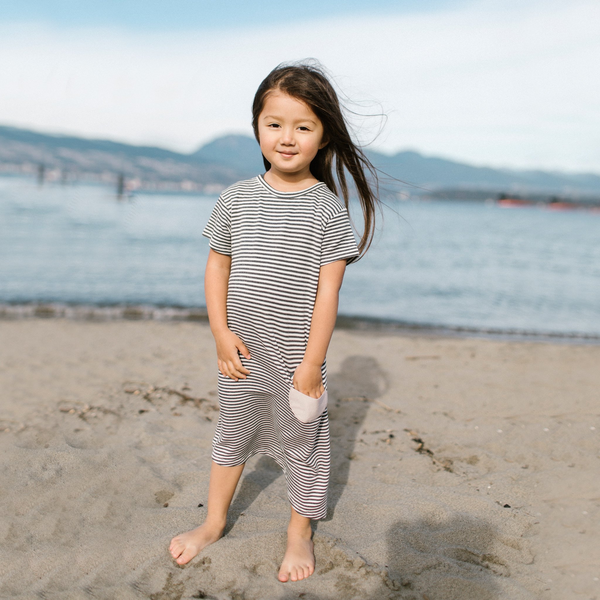 Asymmetric T-shirt Dress in black and white stripes with a monster peek-a-boo pocket, perfect for toddlers.