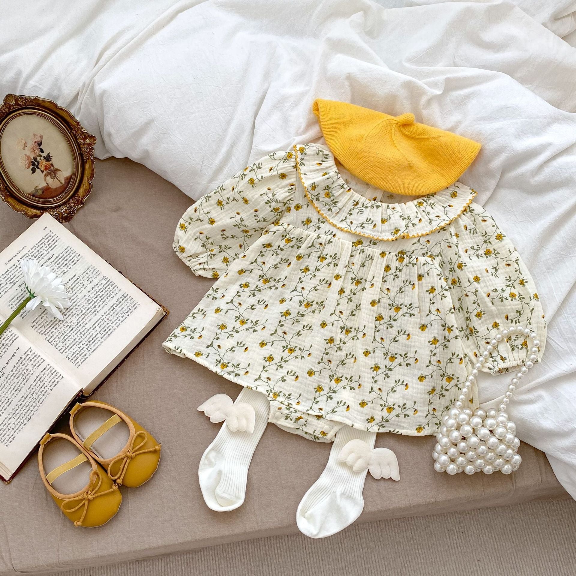 A baby girl wearing an apricot floral dress with a loose fit, perfect for autumn and spring seasons.