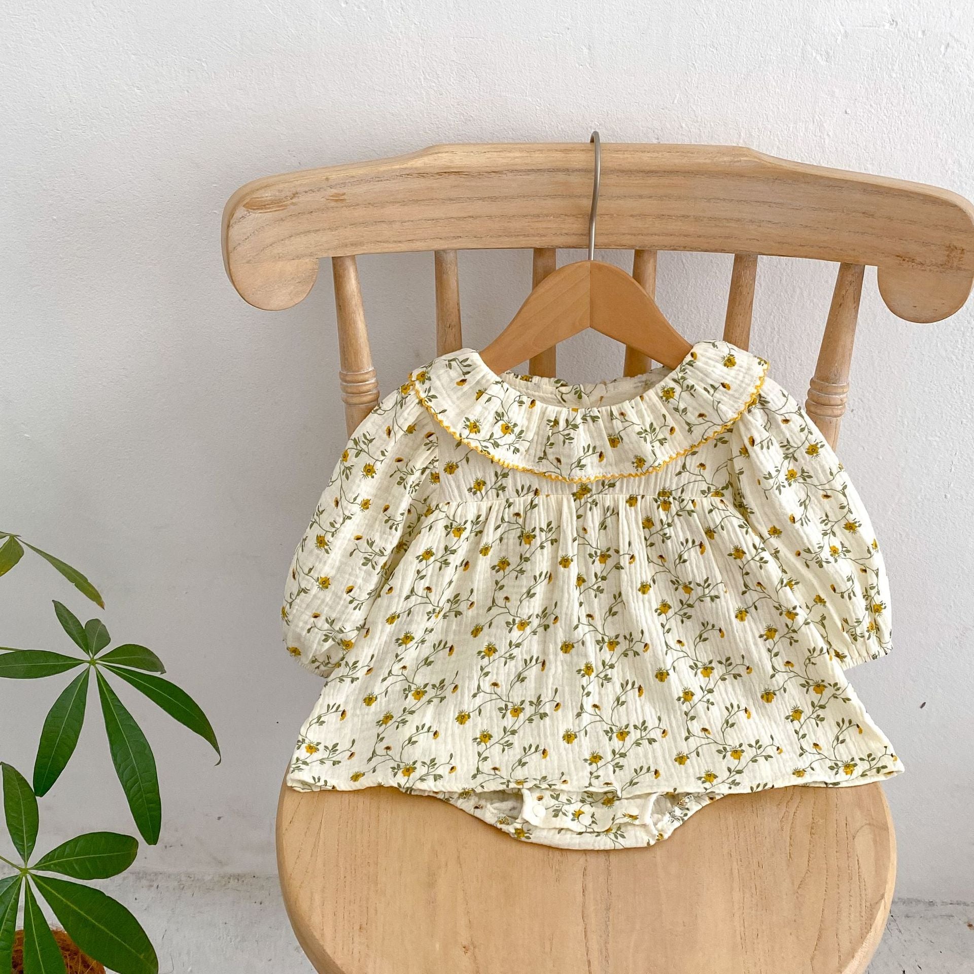 A baby girl wearing an apricot floral dress with a loose fit, perfect for autumn and spring seasons.