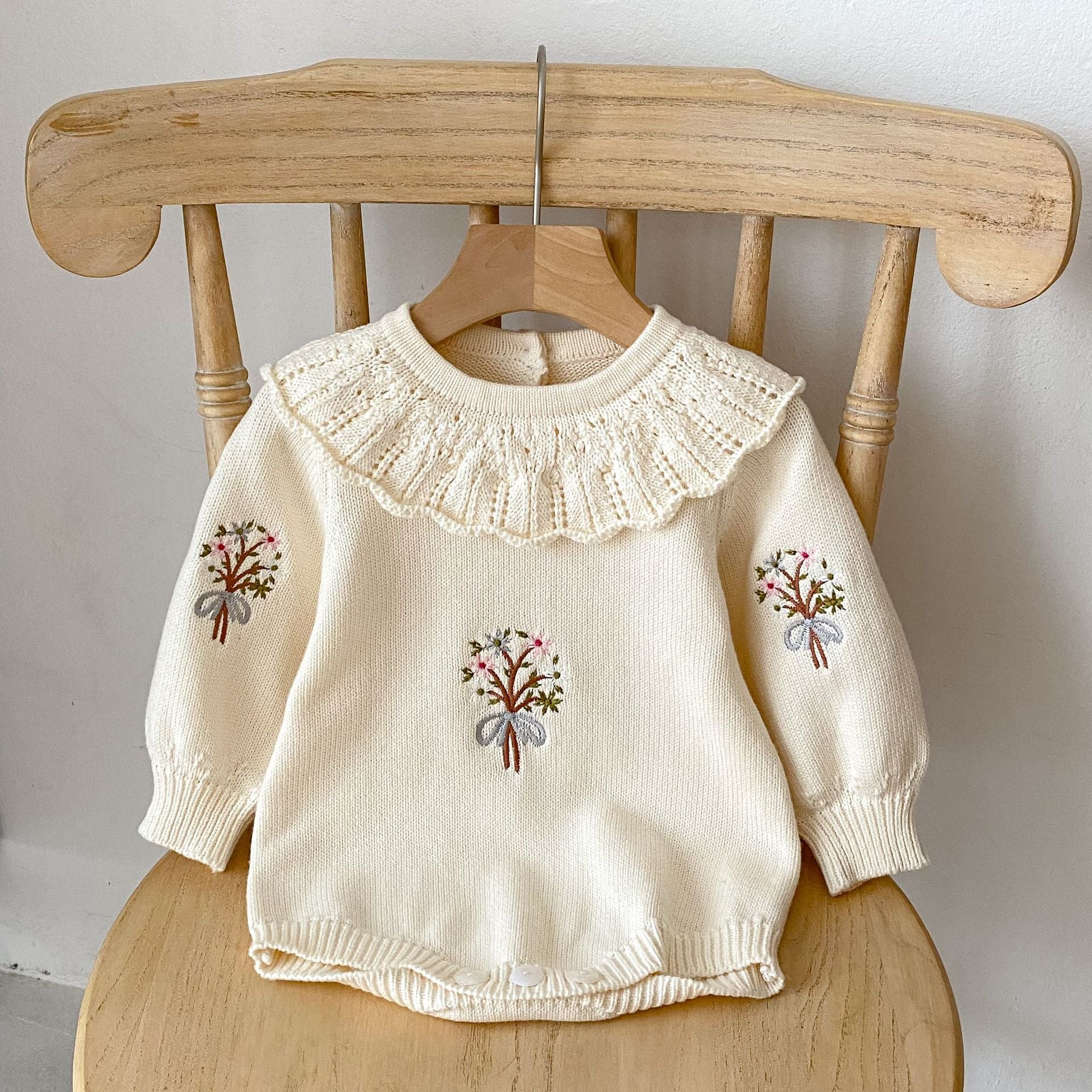 A cozy autumn knitted onesie for baby girls, featuring floral embroidery in beige and brown colors, perfect for the fall season.