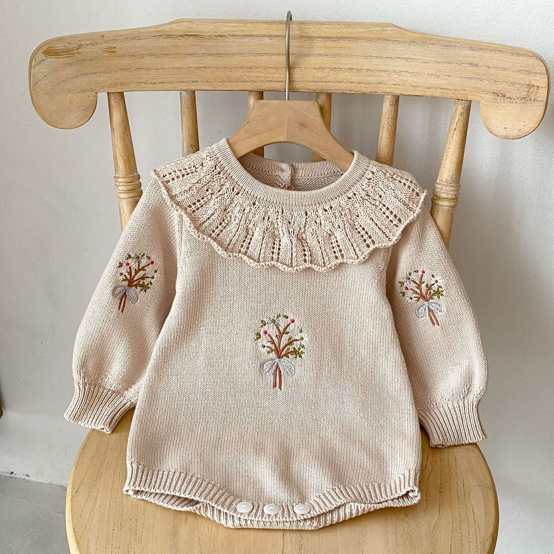 A cozy autumn knitted onesie for baby girls, featuring floral embroidery in beige and brown colors, perfect for the fall season.