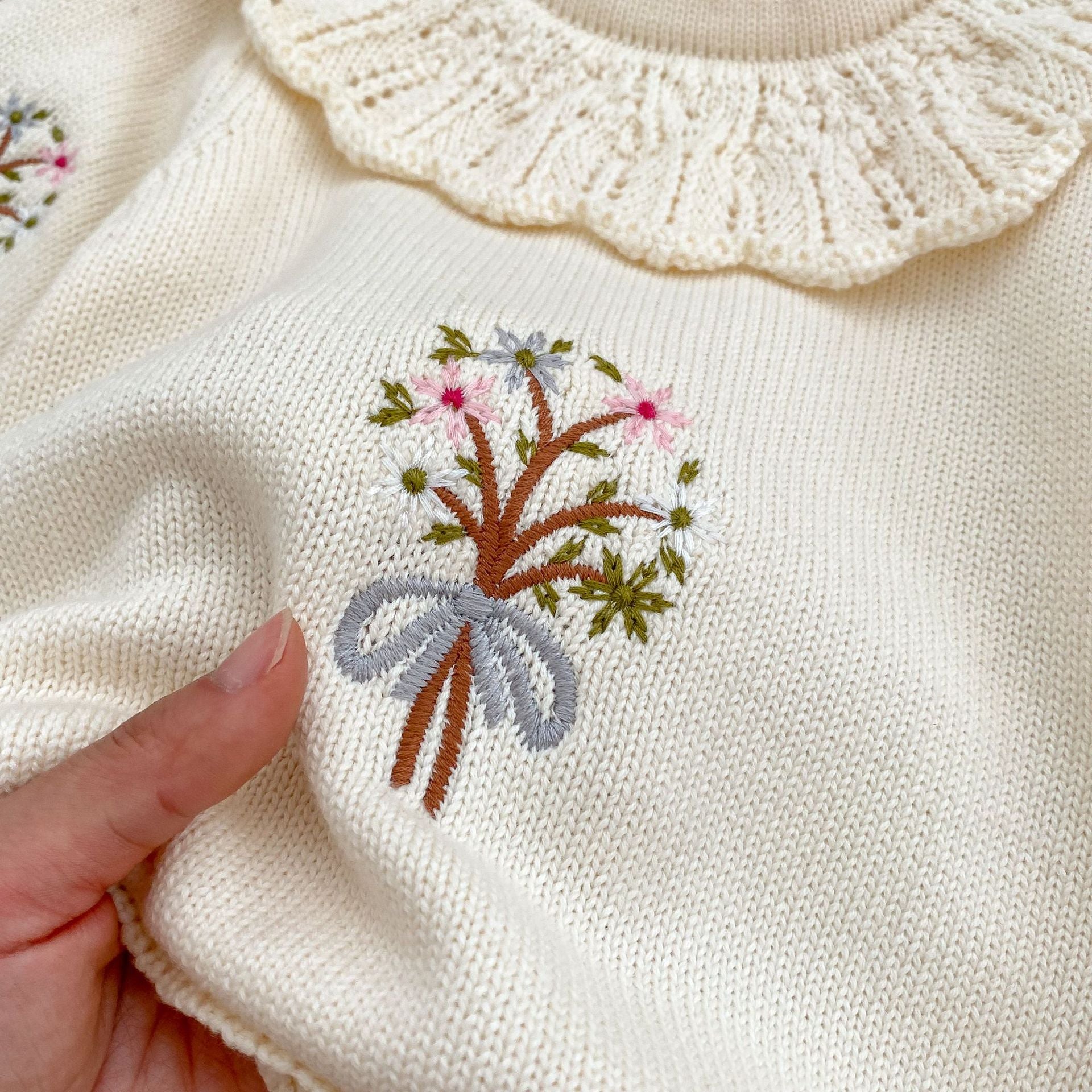 A cozy autumn knitted onesie for baby girls, featuring floral embroidery in beige and brown colors, perfect for the fall season.