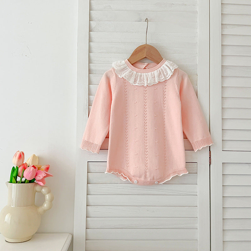 A baby girl wearing a long-sleeved hollow-out striped dress in pink and blue, showcasing a stylish autumn design.