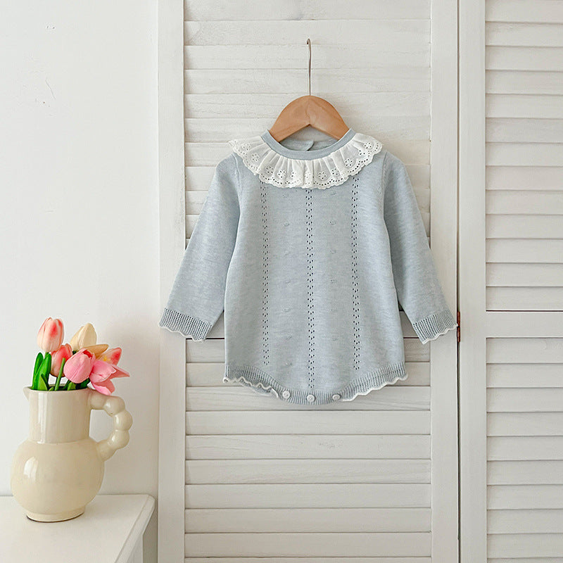 A baby girl wearing a long-sleeved hollow-out striped dress in pink and blue, showcasing a stylish autumn design.