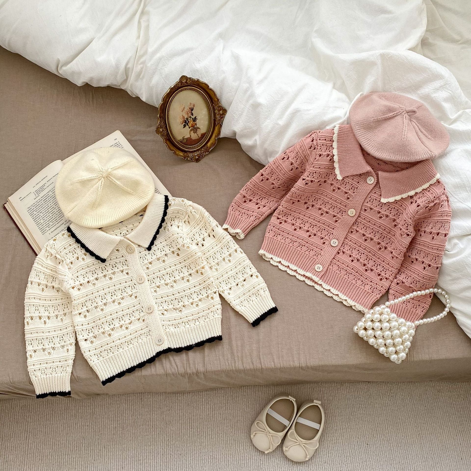 A pink and beige hollow carved design cardigan for baby girls, showcasing its intricate pattern and soft cotton material.