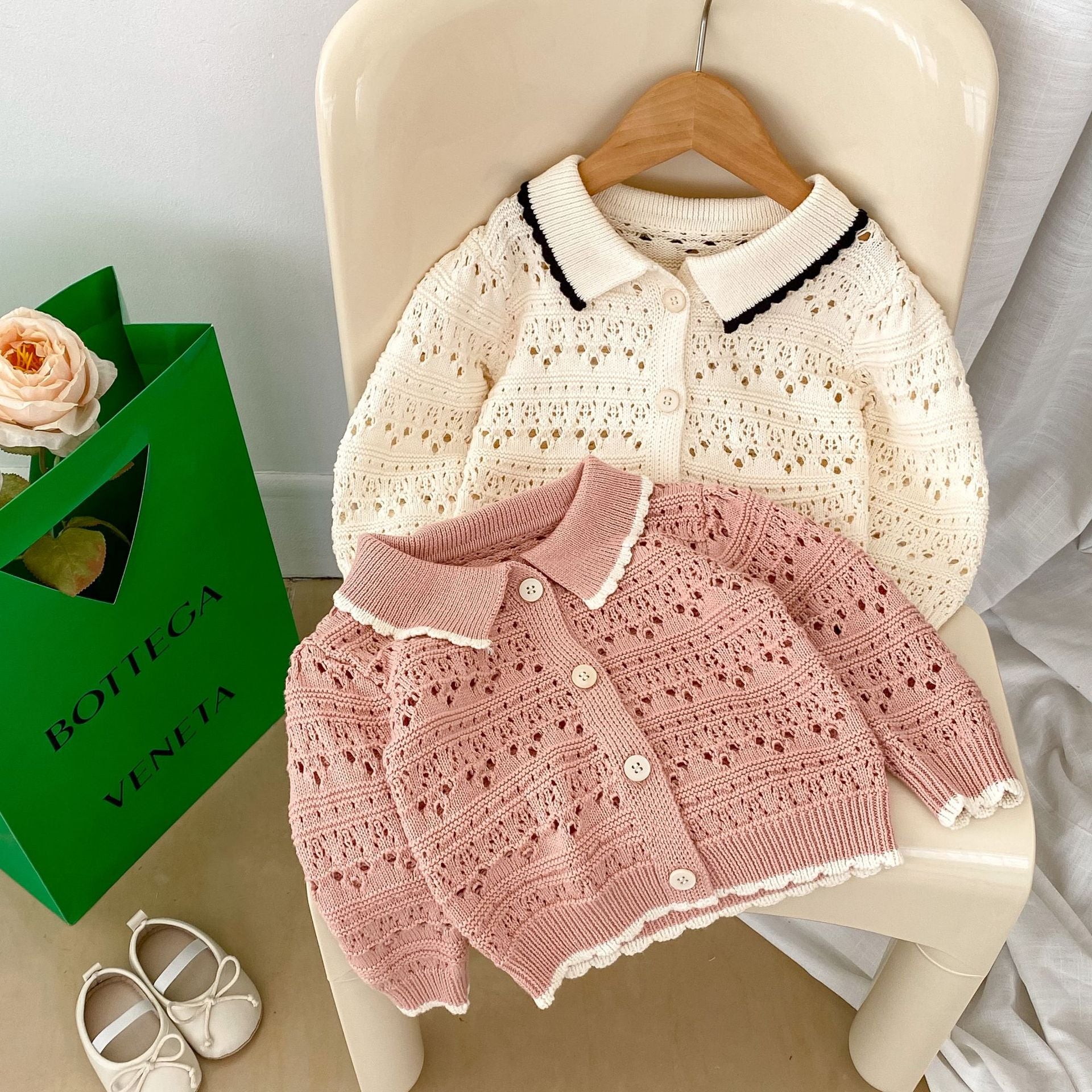 A pink and beige hollow carved design cardigan for baby girls, showcasing its intricate pattern and soft cotton material.