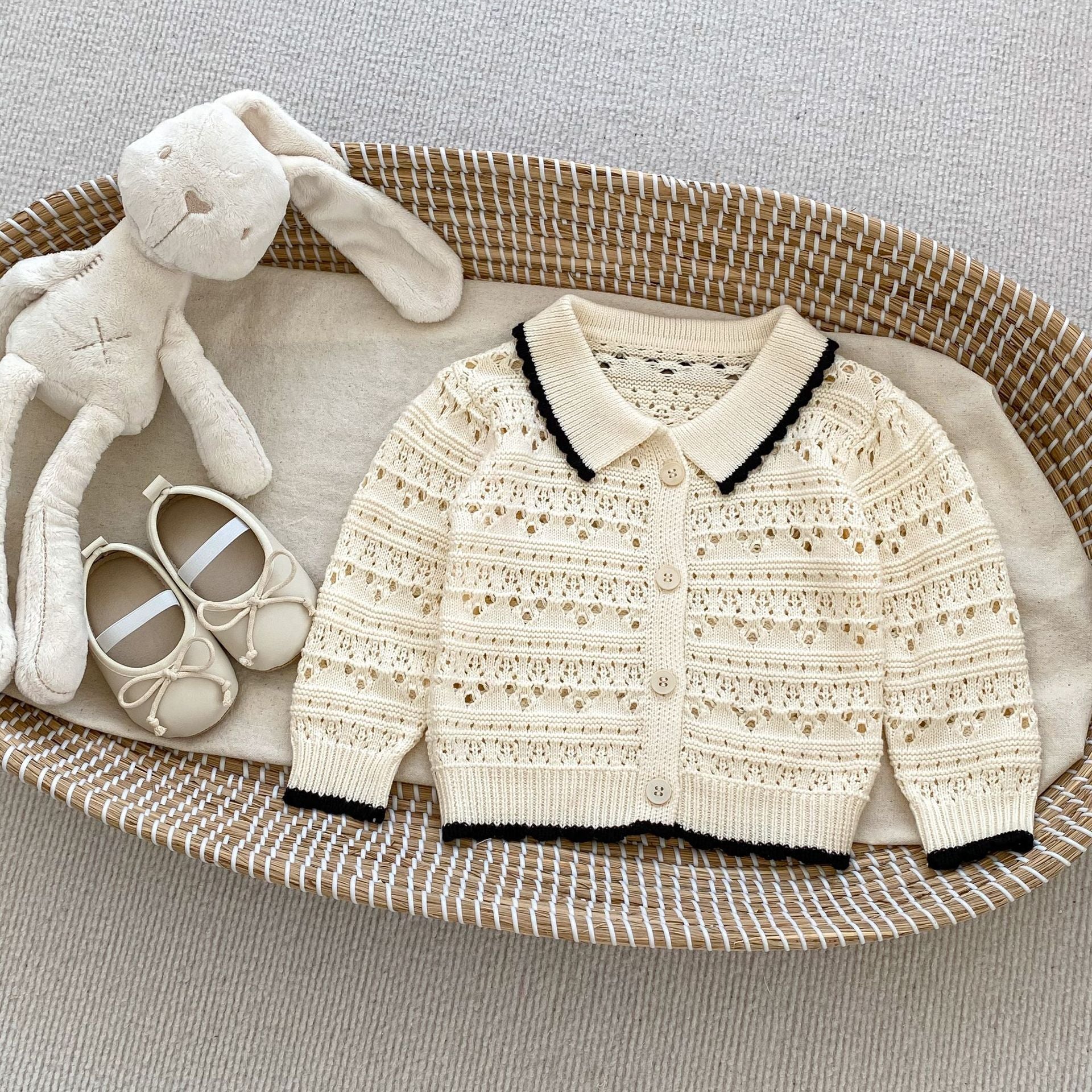 A pink and beige hollow carved design cardigan for baby girls, showcasing its intricate pattern and soft cotton material.