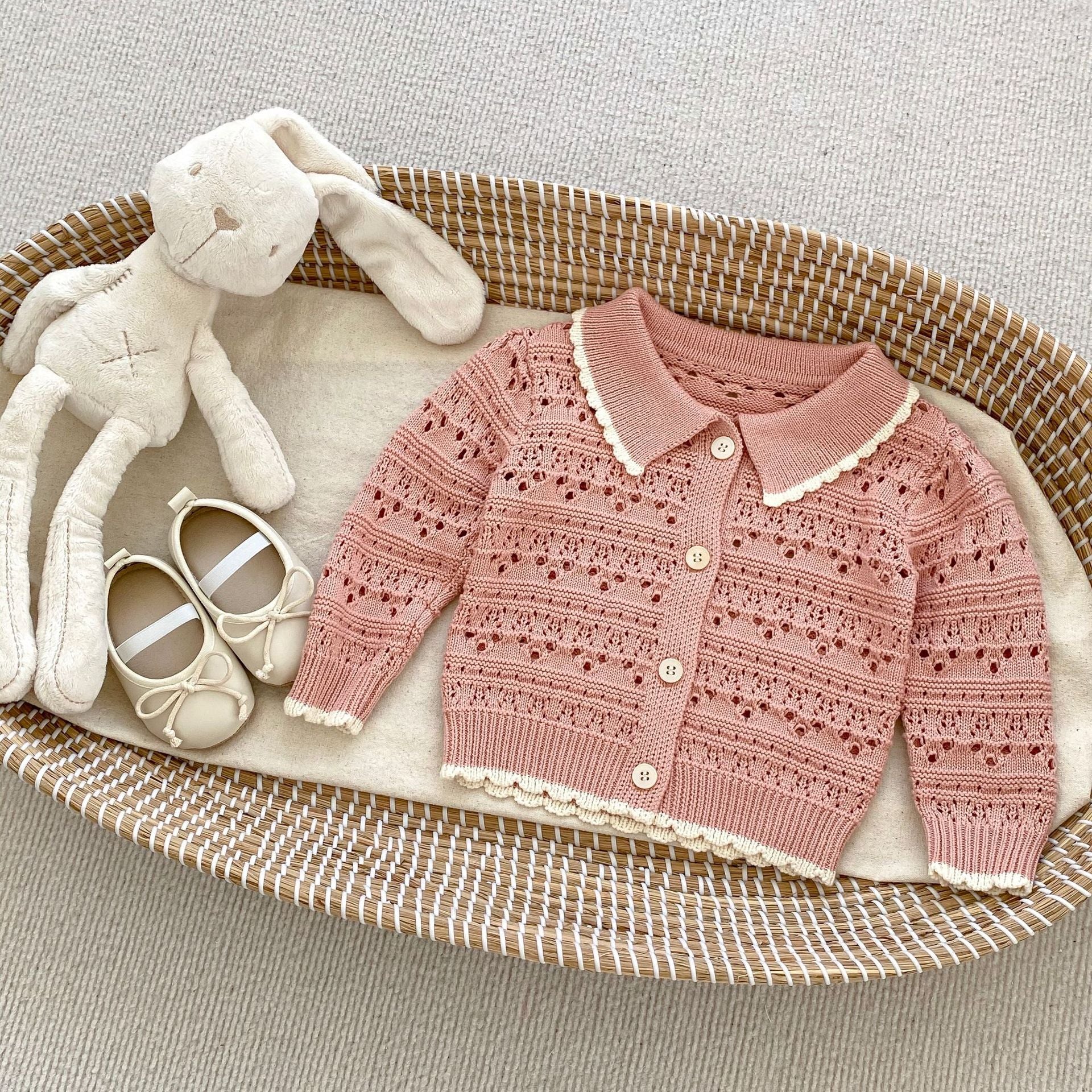 A pink and beige hollow carved design cardigan for baby girls, showcasing its intricate pattern and soft cotton material.