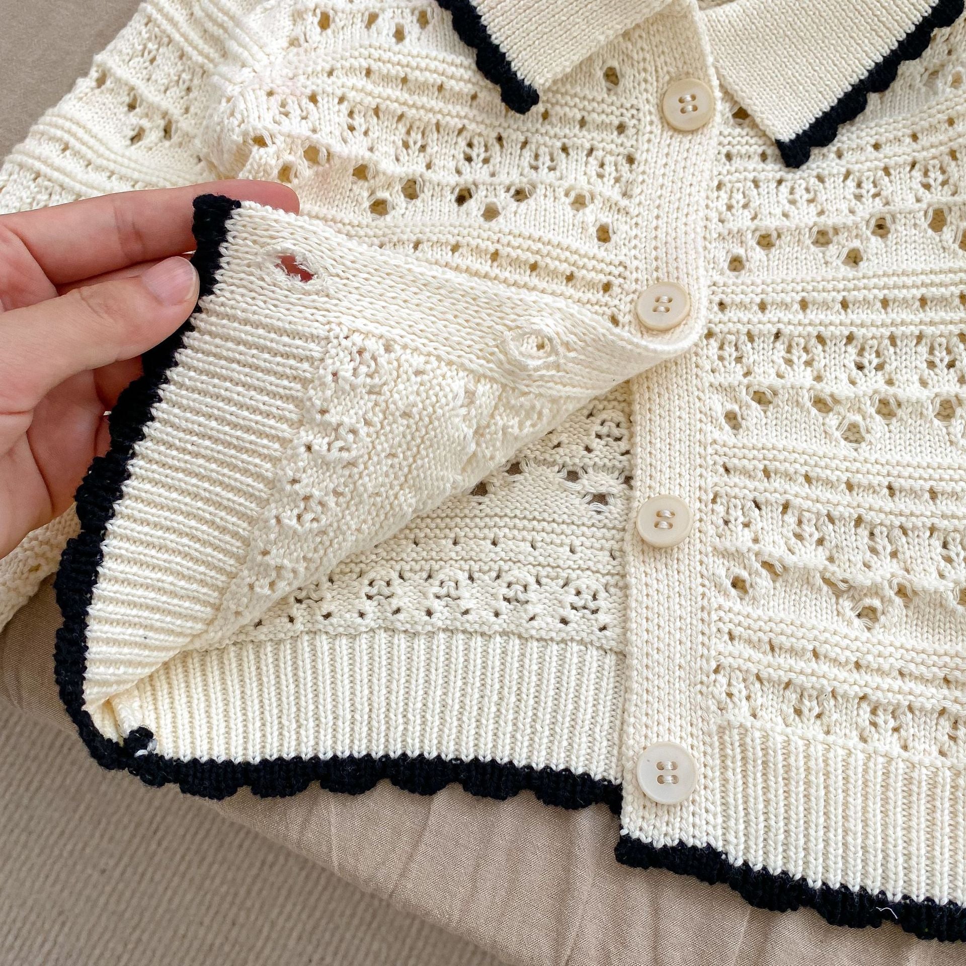 A pink and beige hollow carved design cardigan for baby girls, showcasing its intricate pattern and soft cotton material.