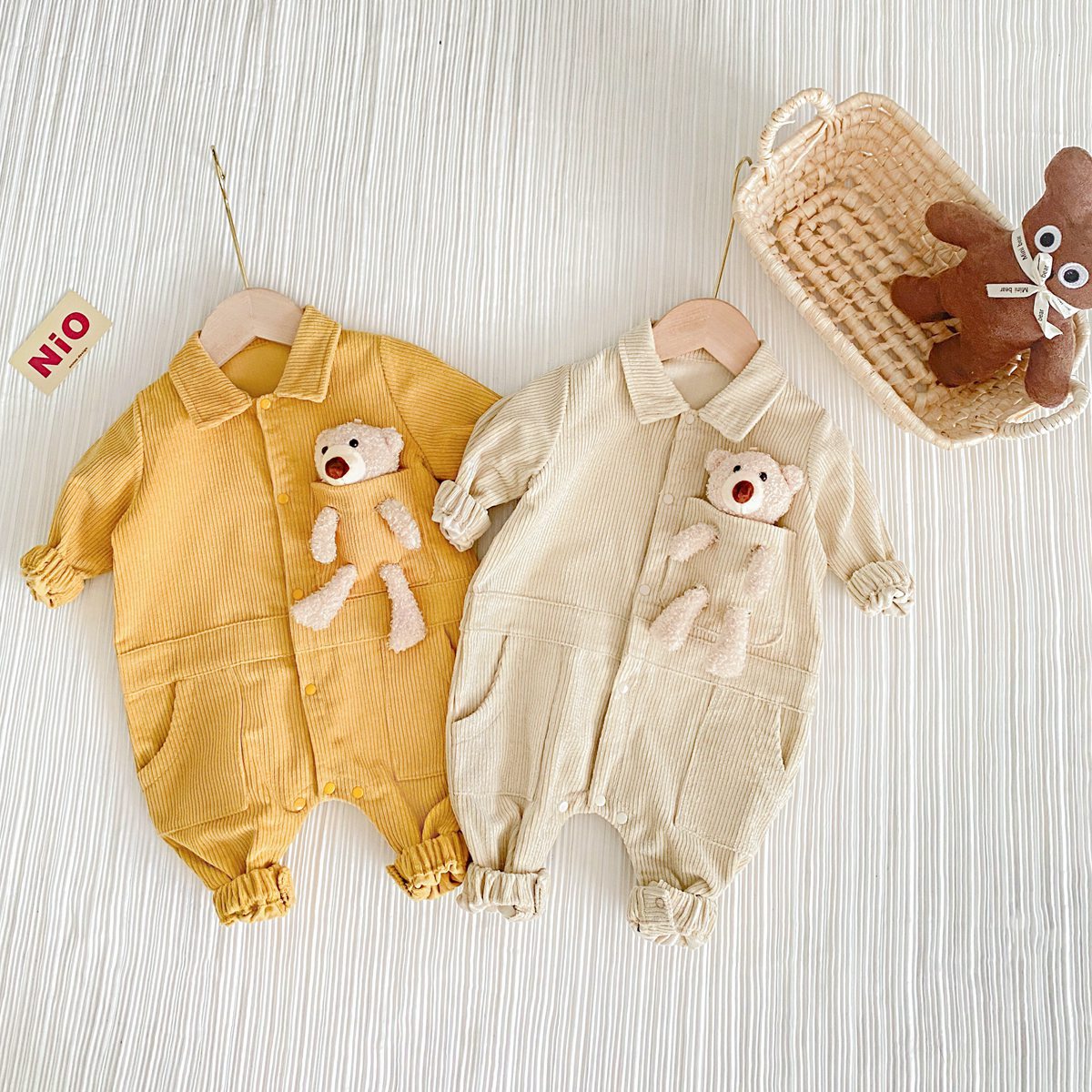 Baby romper featuring a 3D cartoon bear patch design, made from soft corduroy fabric with a button front closure, available in yellow and apricot.