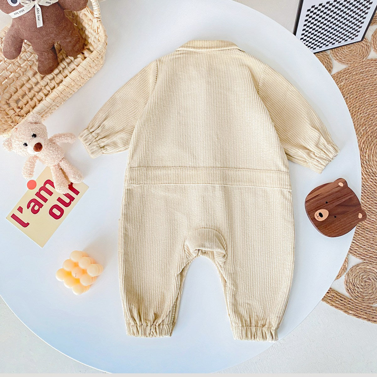 Baby romper featuring a 3D cartoon bear patch design, made from soft corduroy fabric with a button front closure, available in yellow and apricot.