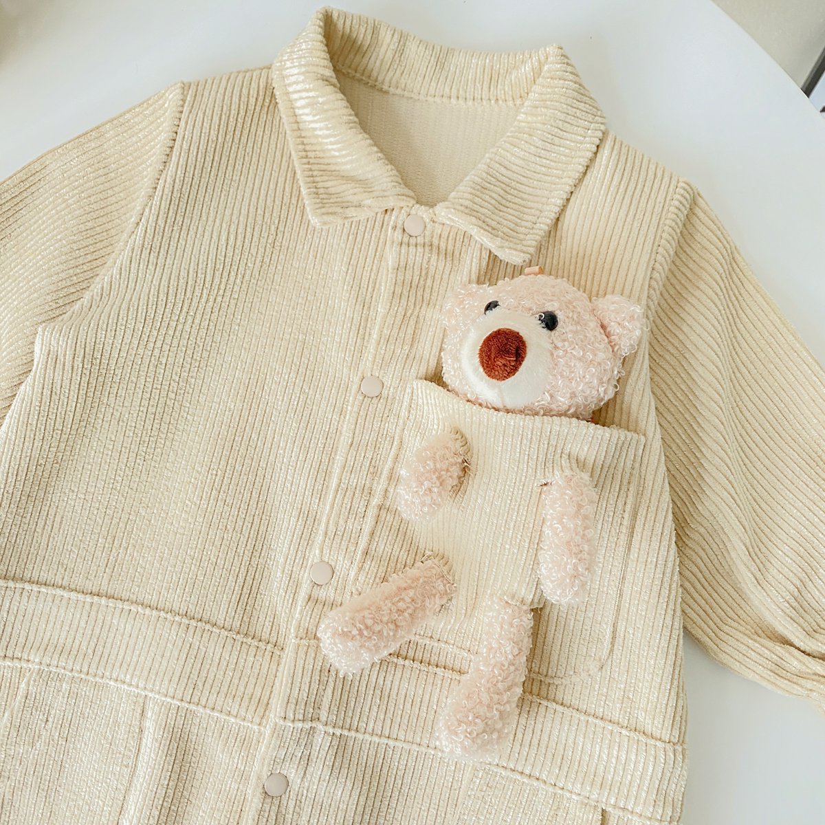 Baby romper featuring a 3D cartoon bear patch design, made from soft corduroy fabric with a button front closure, available in yellow and apricot.