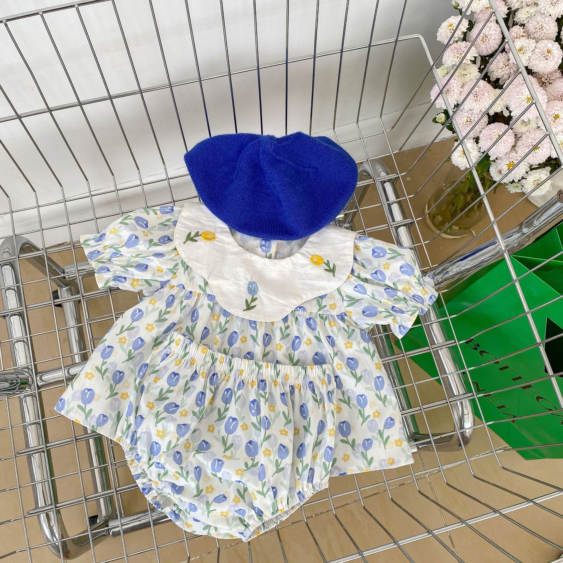 Baby girl wearing a blue floral embroidered crewneck top with doll neck design, showcasing delicate flower patterns.