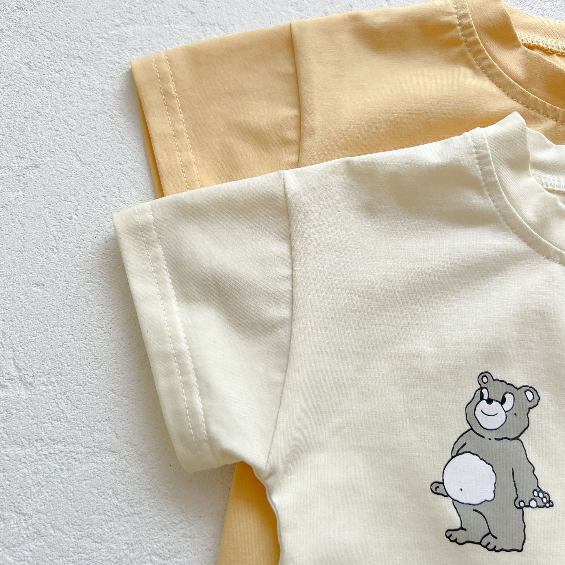 Baby boy and girl bear print onesies in white and yellow colors, featuring a cozy O-neck design made from soft cotton material.