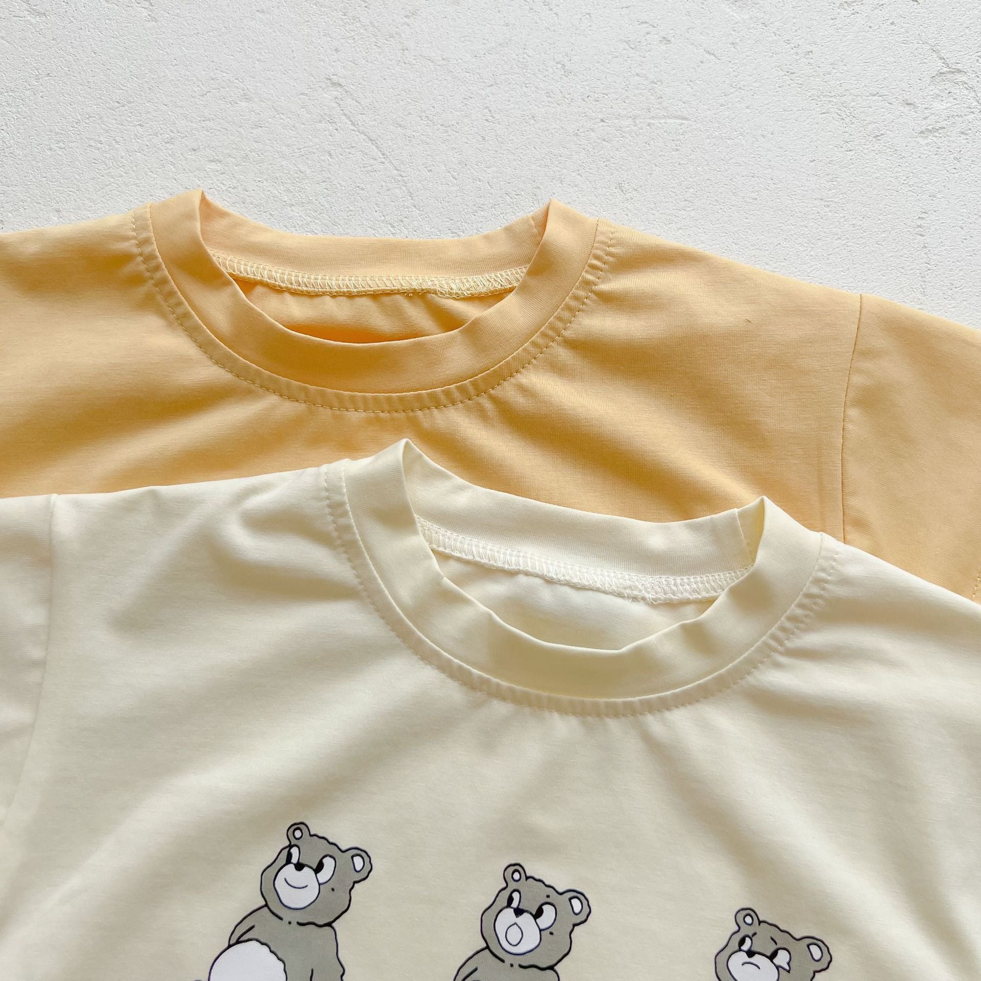 Baby boy and girl bear print onesies in white and yellow colors, featuring a cozy O-neck design made from soft cotton material.