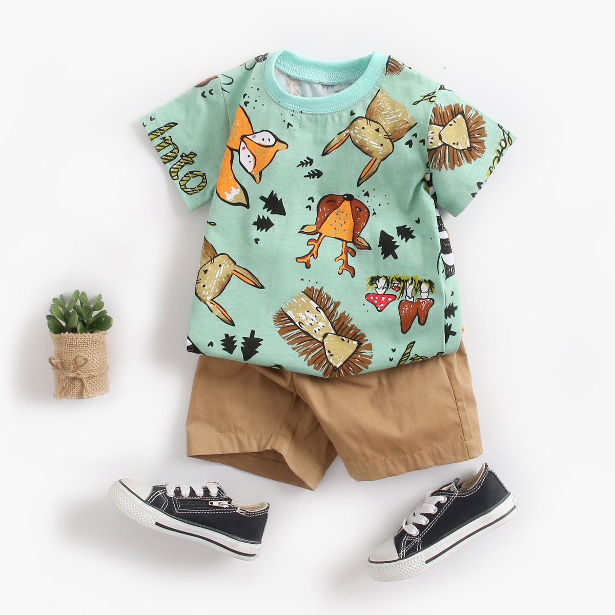 Baby boy wearing a vibrant green animal print top and solid color shorts, perfect for summer outings.