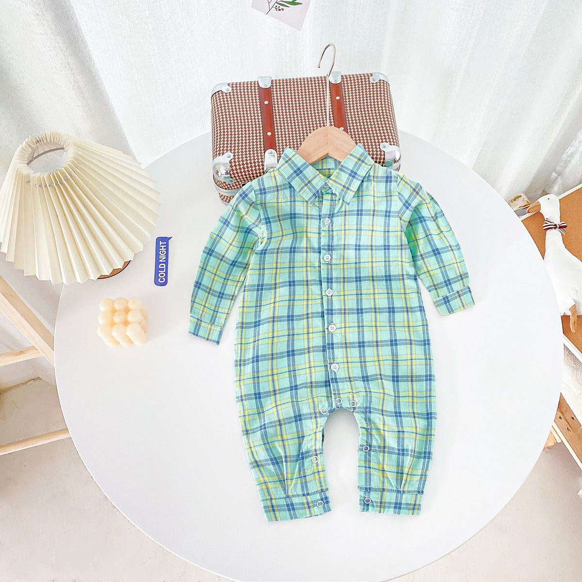 Baby boy wearing a classic plaid pattern long sleeve romper with lapel design in green and apricot colors.