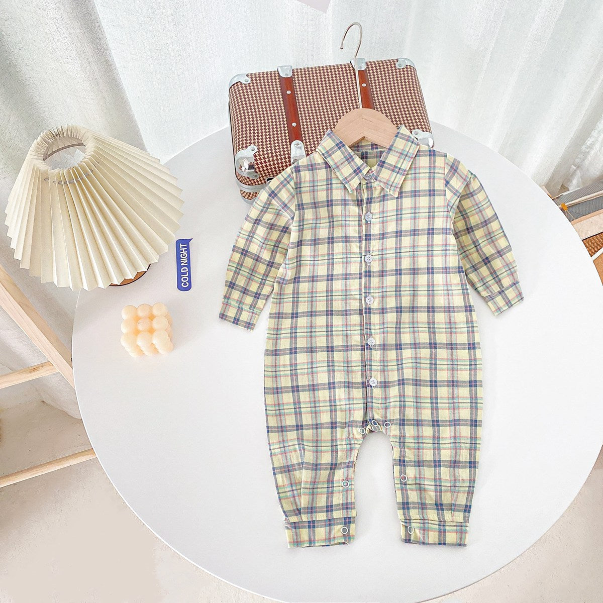 Baby boy wearing a classic plaid pattern long sleeve romper with lapel design in green and apricot colors.